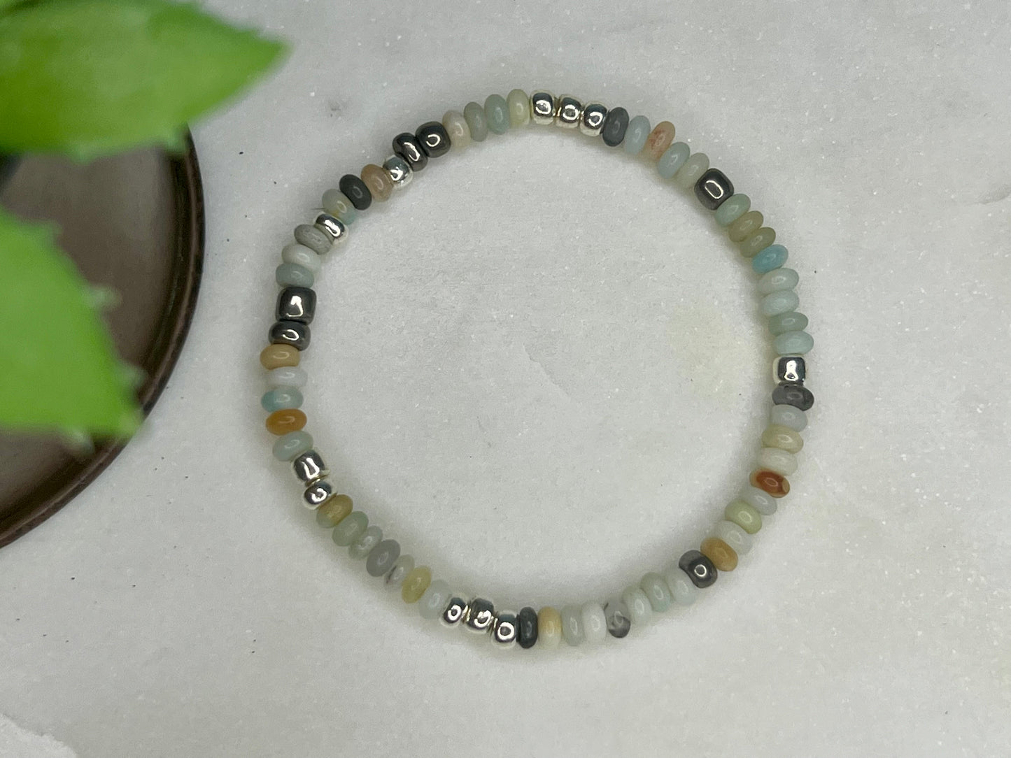 a beaded bracelet on a table next to a potted plant