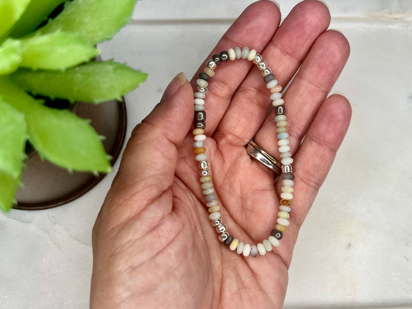 a person holding a beaded bracelet in their hand