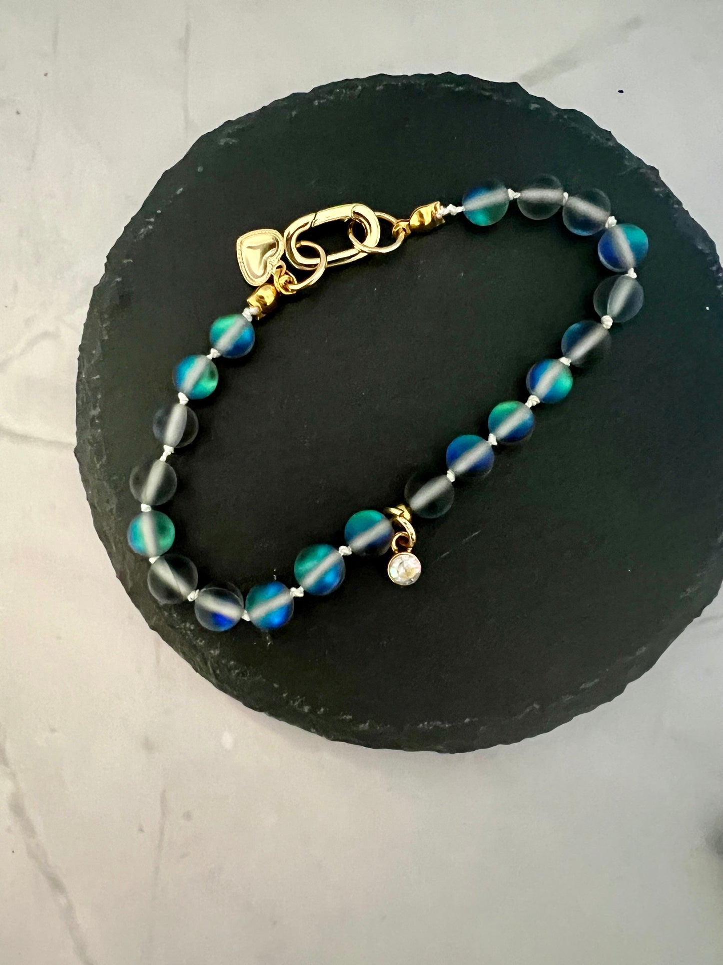 a blue and green beaded bracelet on a black stone