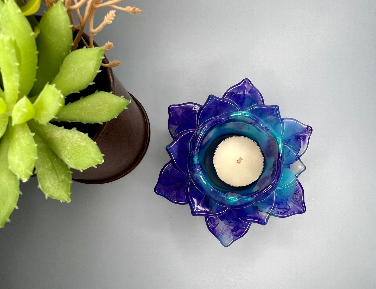 a blue glass candle holder next to a potted plant