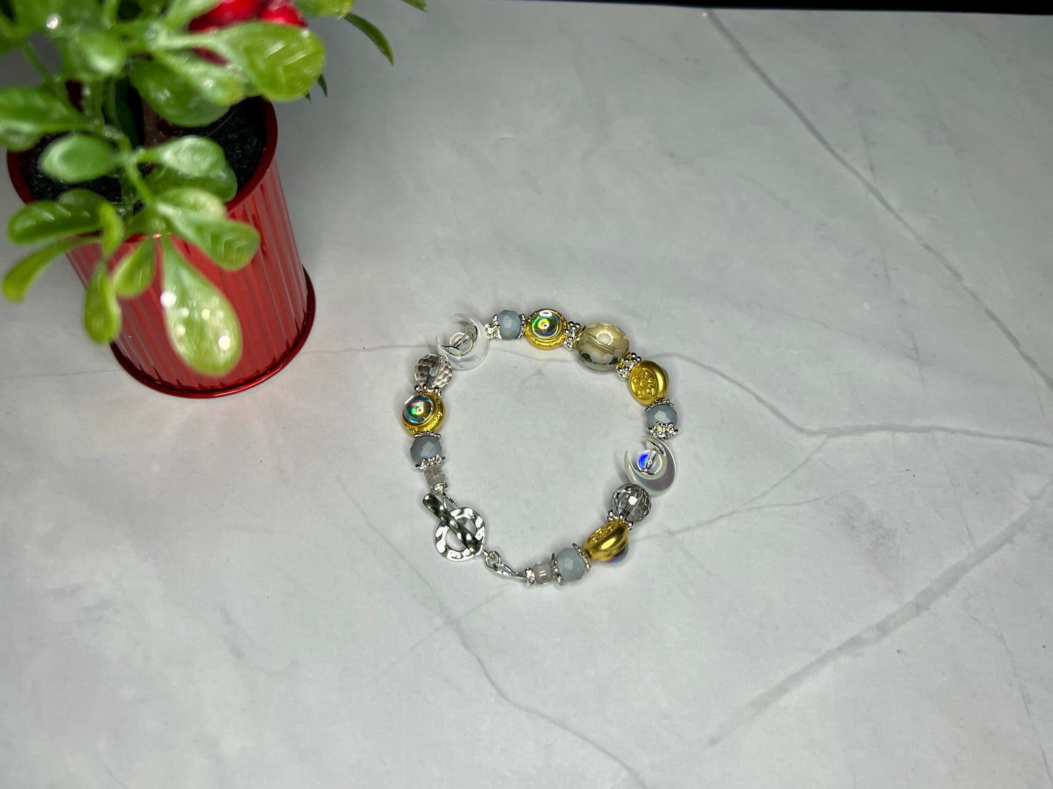 a close up of a bracelet on a table near a potted plant