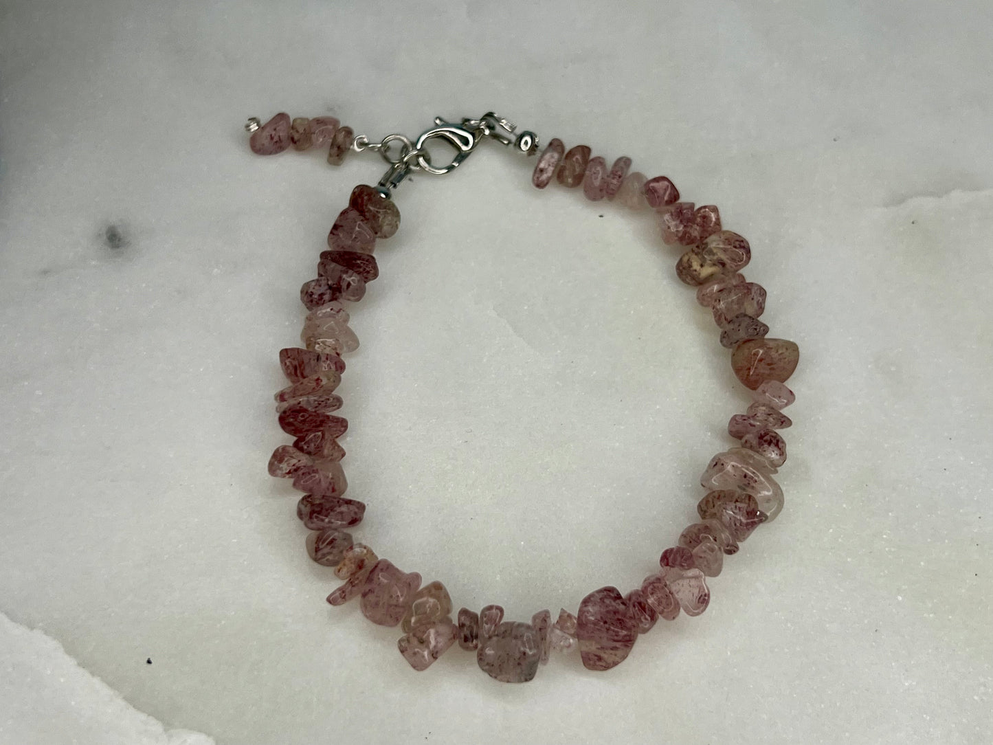 a bracelet with pink beads on a white surface