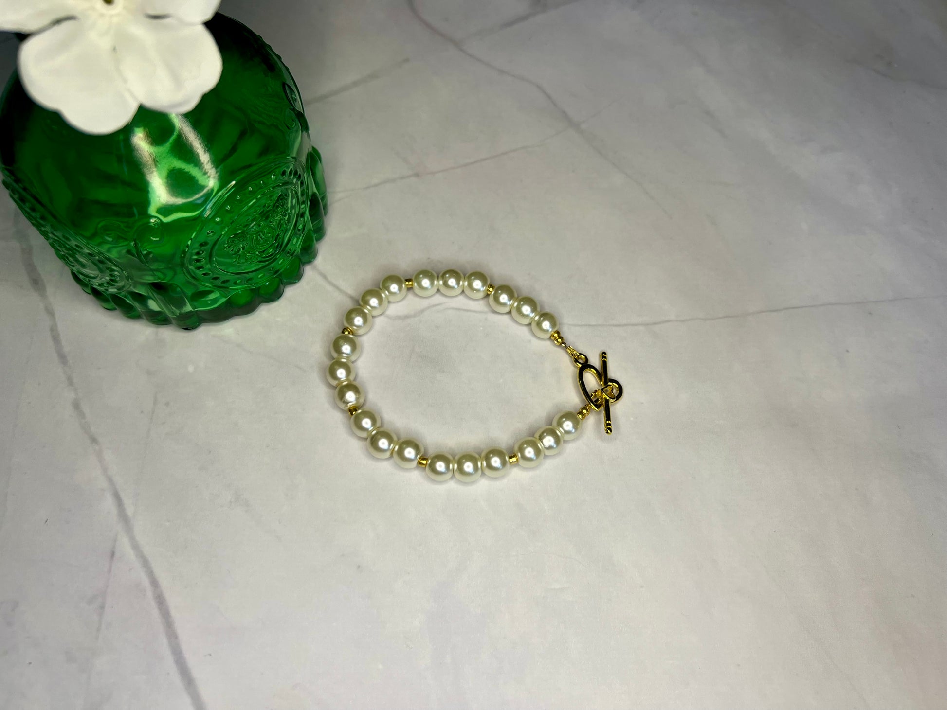 a bracelet with a cross on it next to a green vase