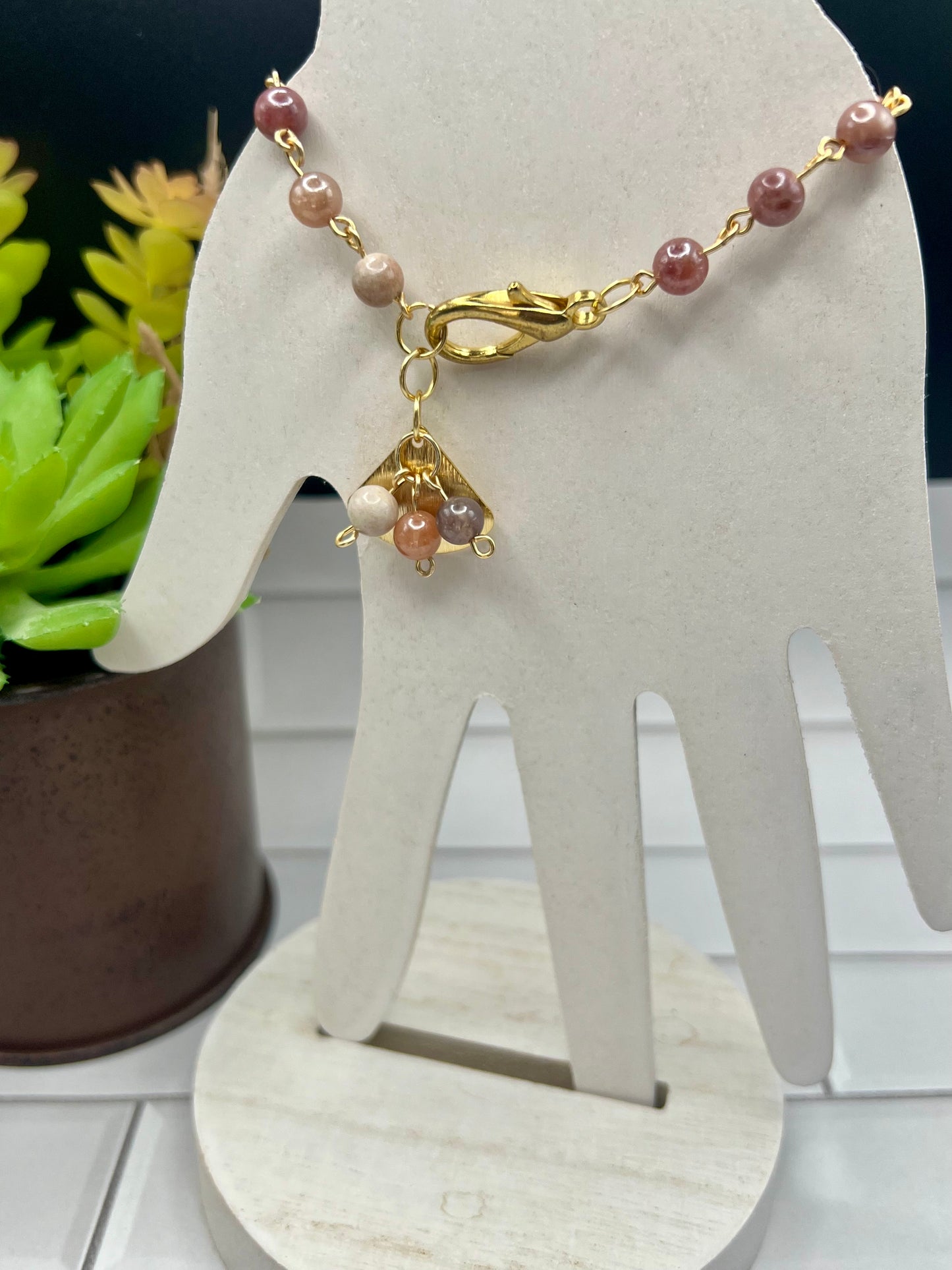 a necklace on a stand next to a potted plant