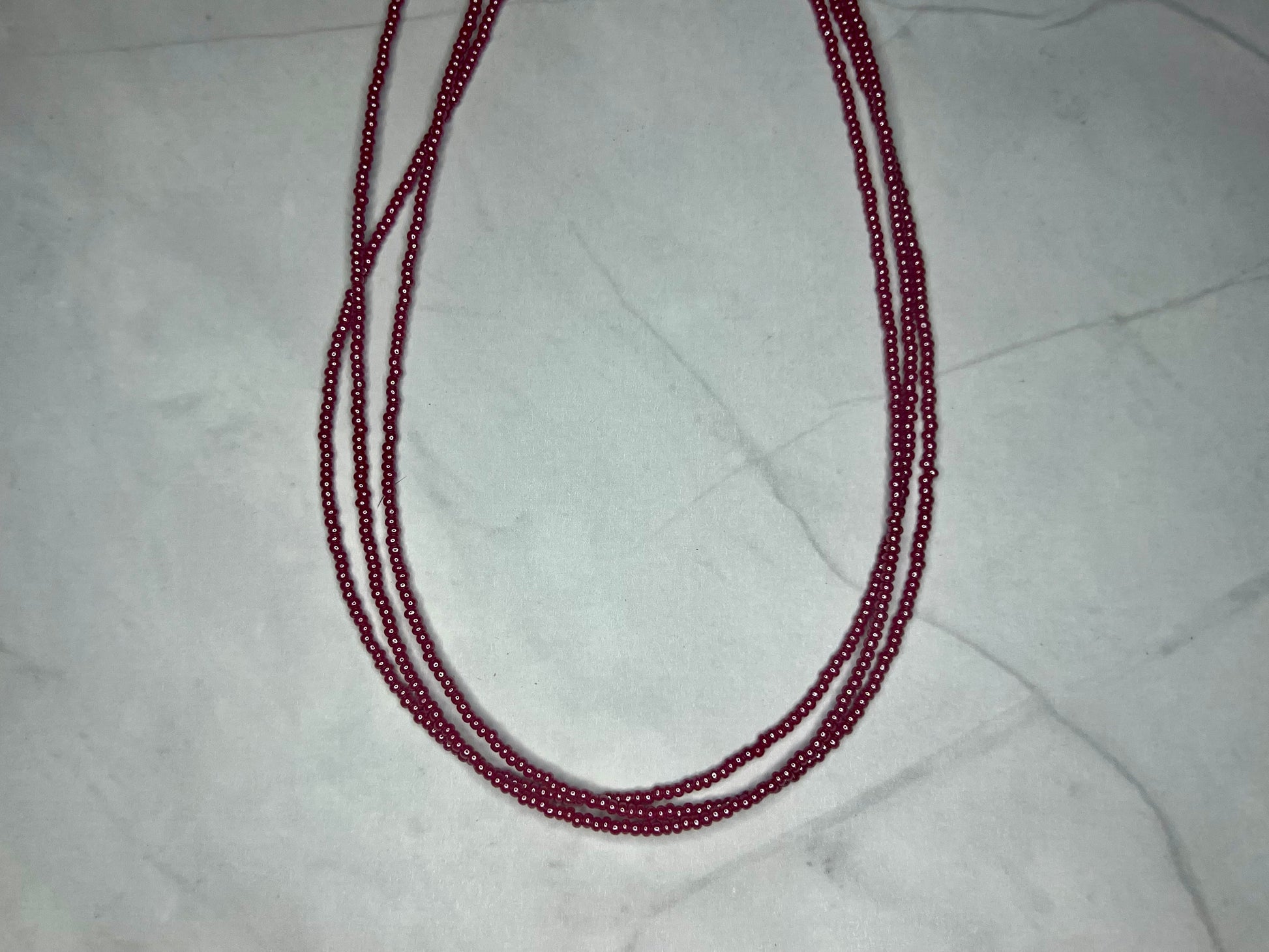 a red beaded necklace on a marble surface