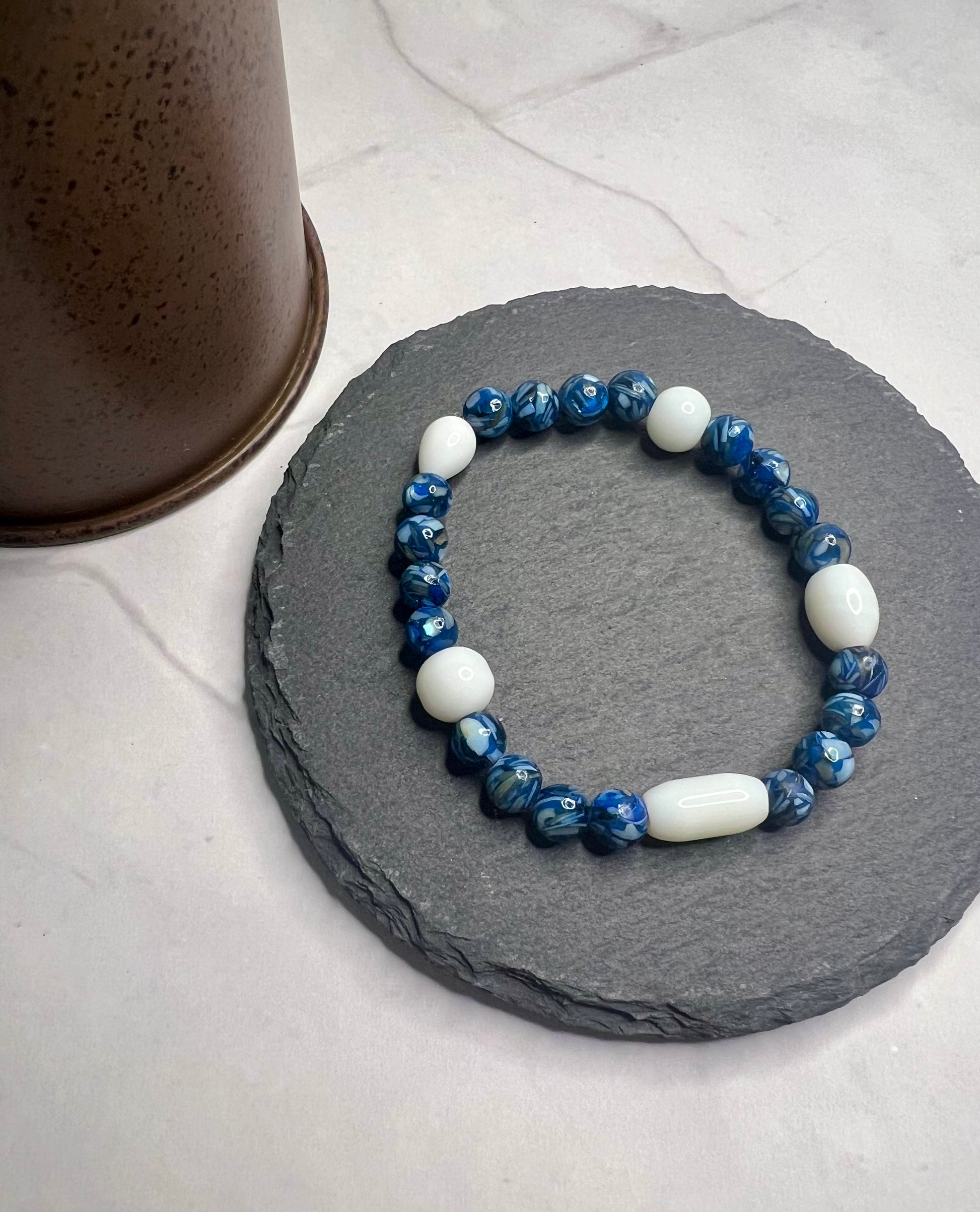 a blue and white beaded bracelet sitting on a stone