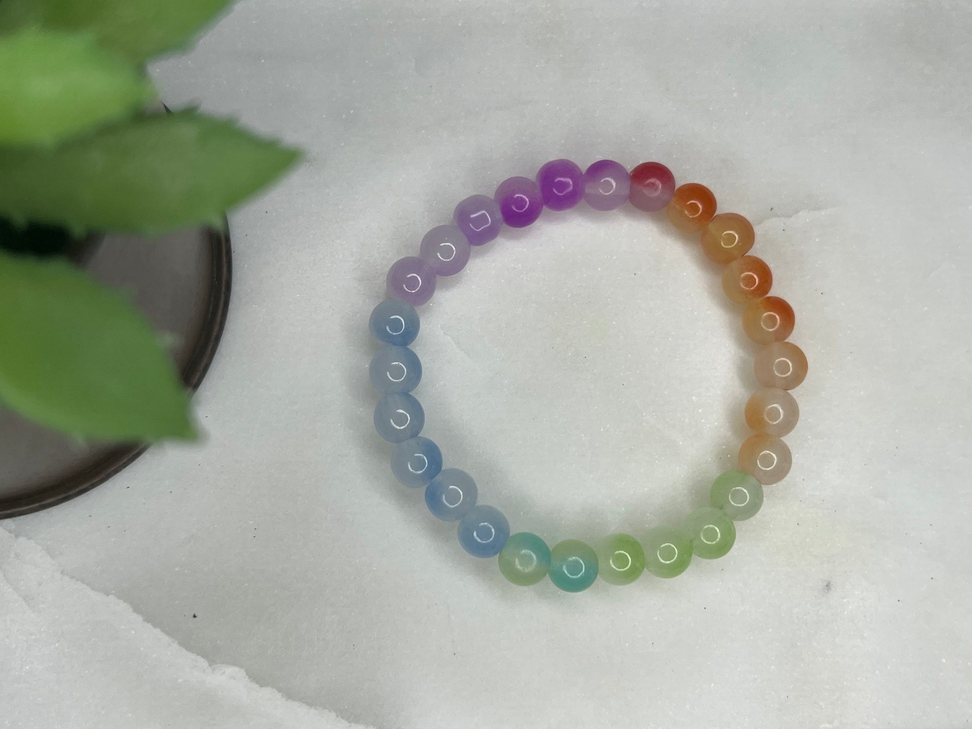 a bracelet made of multicolored beads sits next to a potted plant