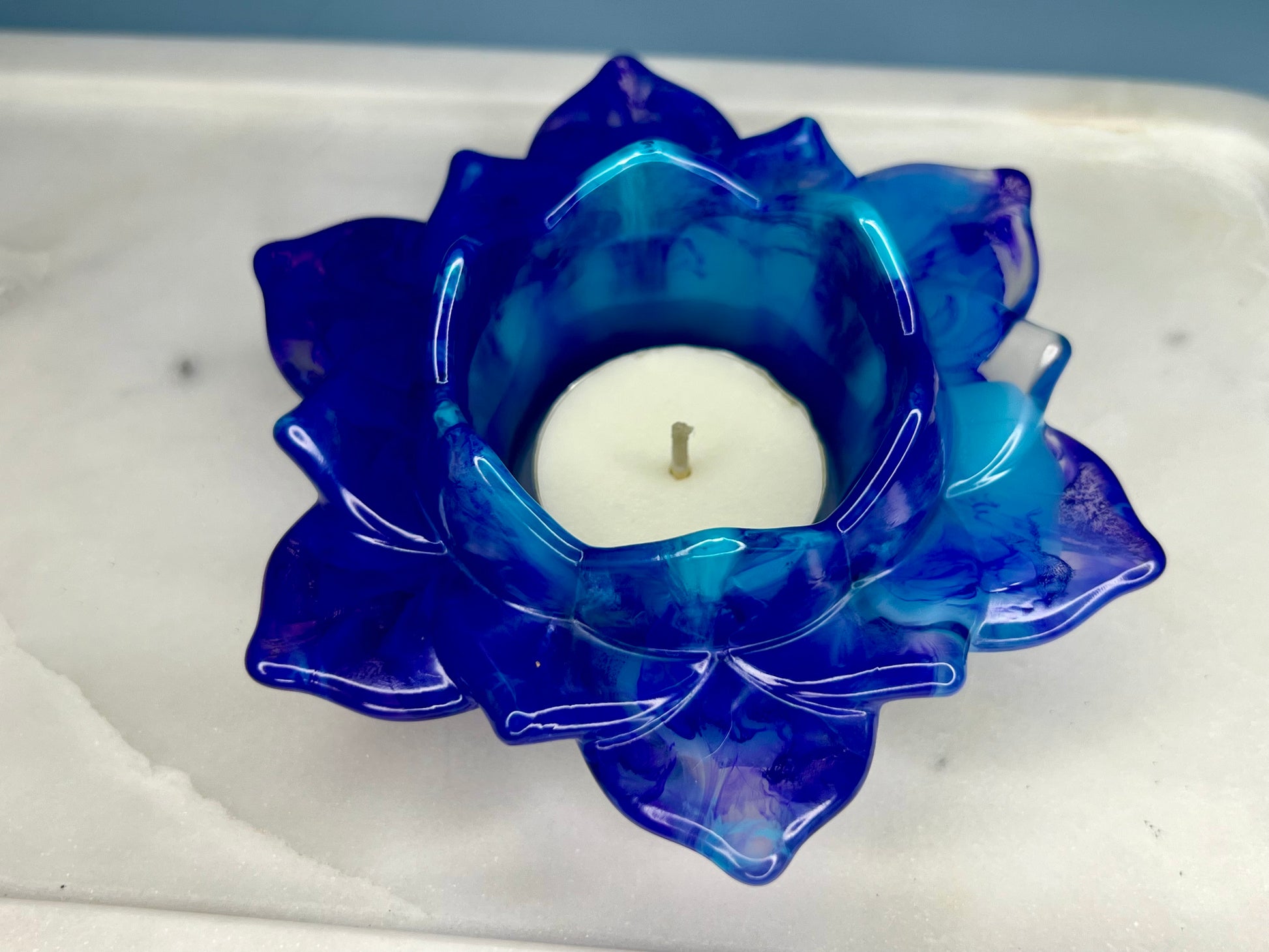 a blue glass candle holder with a white candle