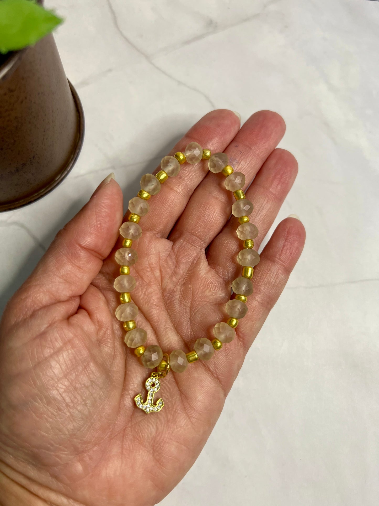 a woman's hand holding a yellow beaded bracelet