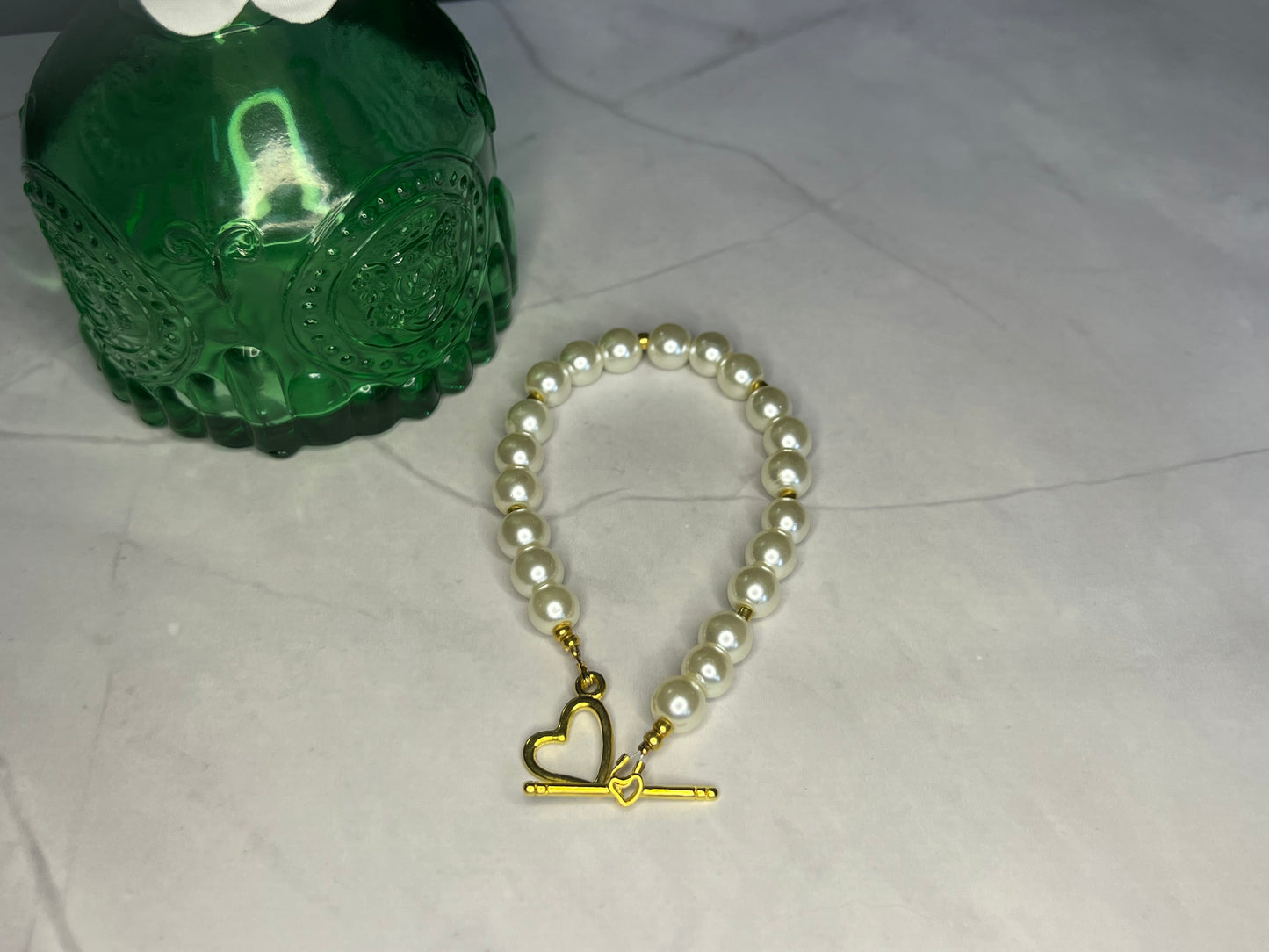 a pearl bracelet with a gold heart charm