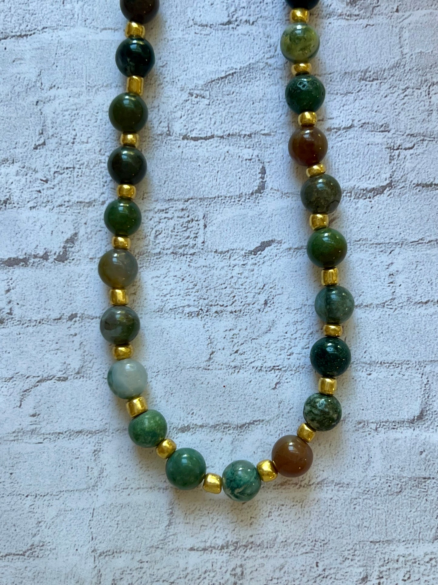 a long necklace with various colored beads on a white brick wall