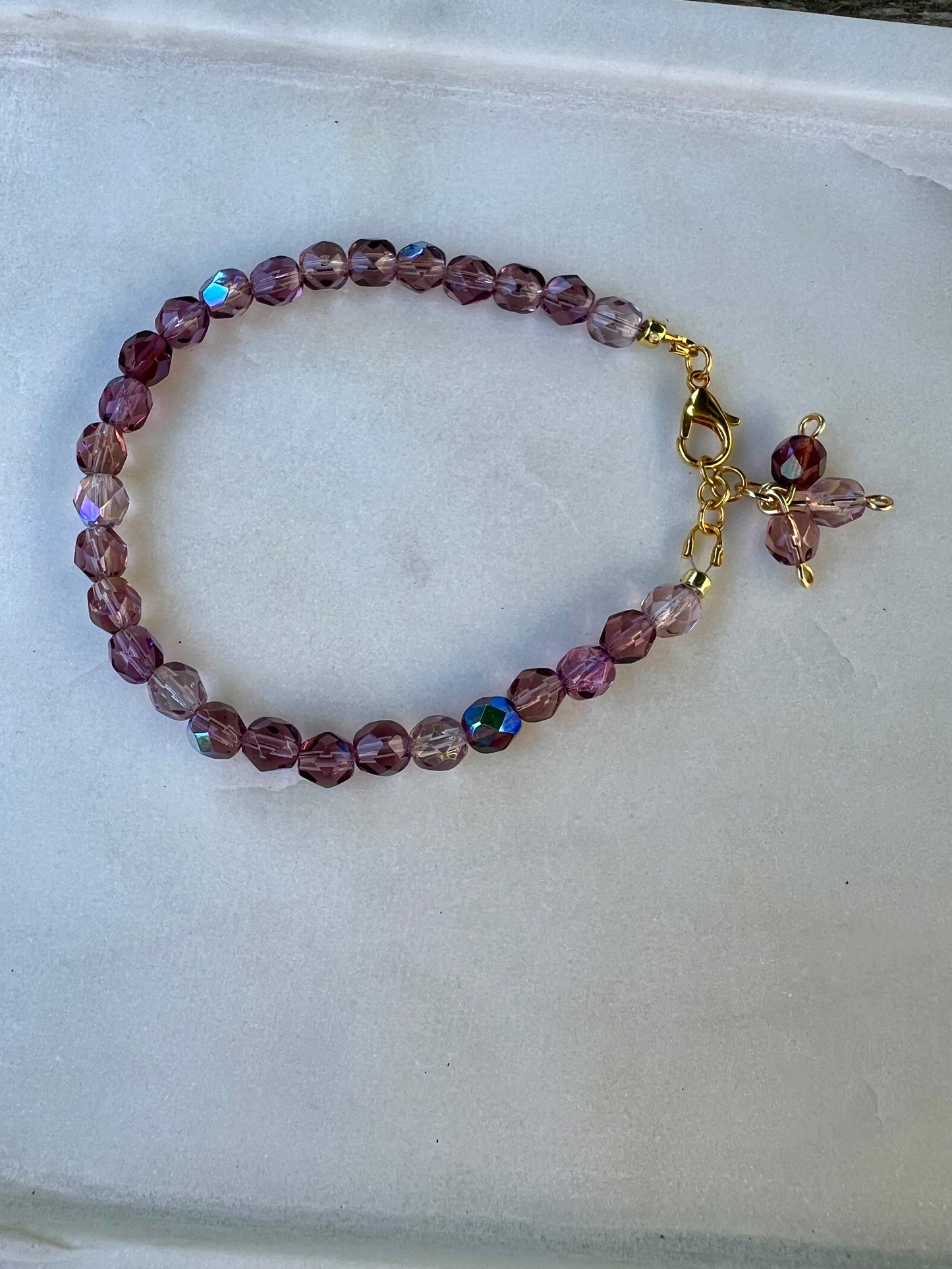 a purple beaded bracelet with a cross charm