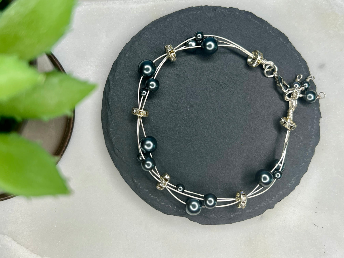 a black and silver beaded bracelet sitting on top of a rock