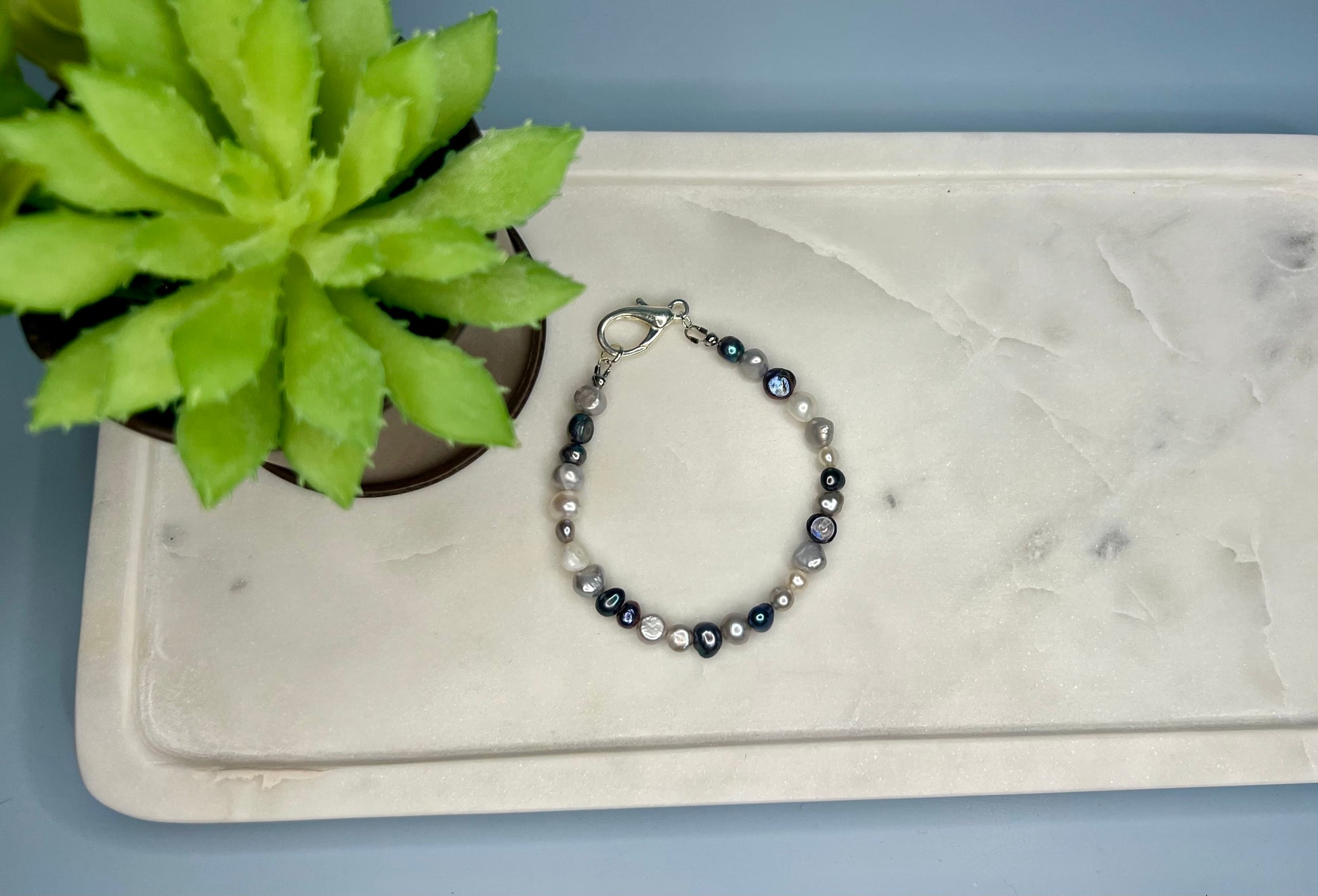 a beaded bracelet sits next to a potted plant