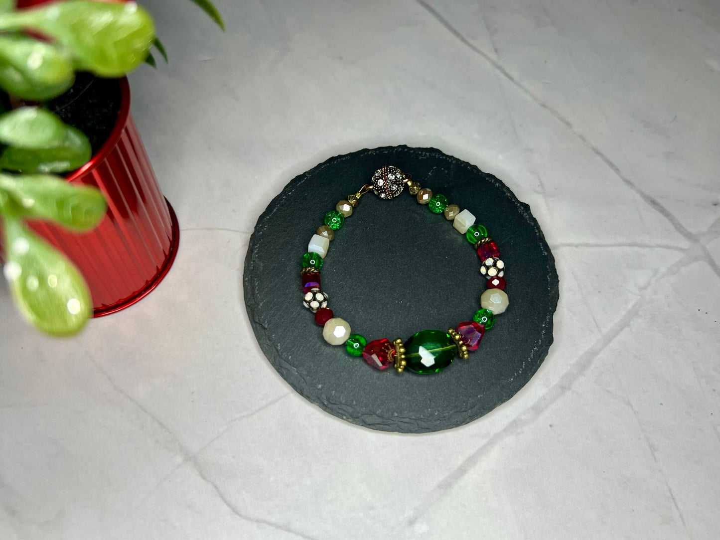 a green and white beaded bracelet next to a potted plant