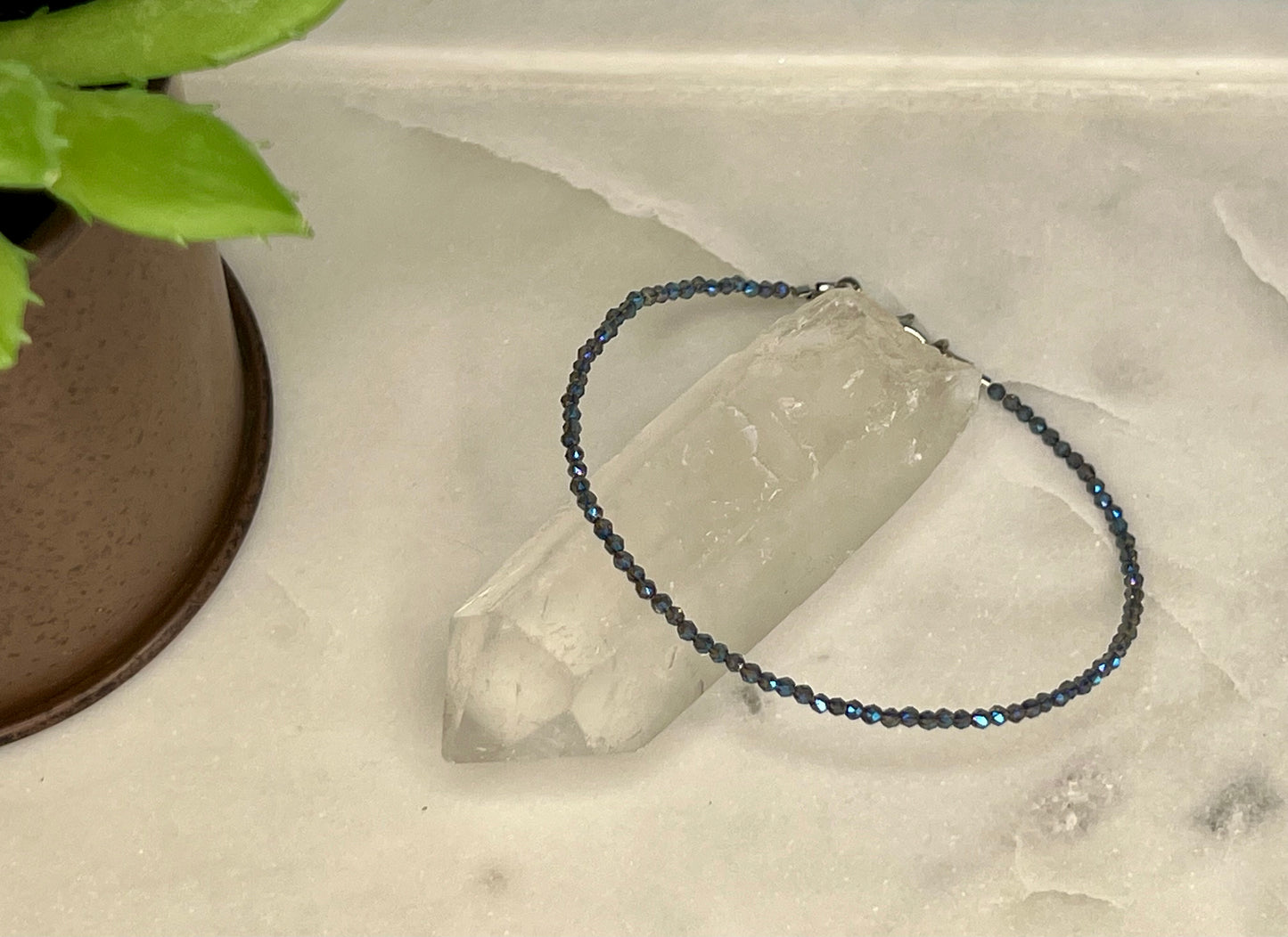 a bracelet sitting on top of a table next to a potted plant