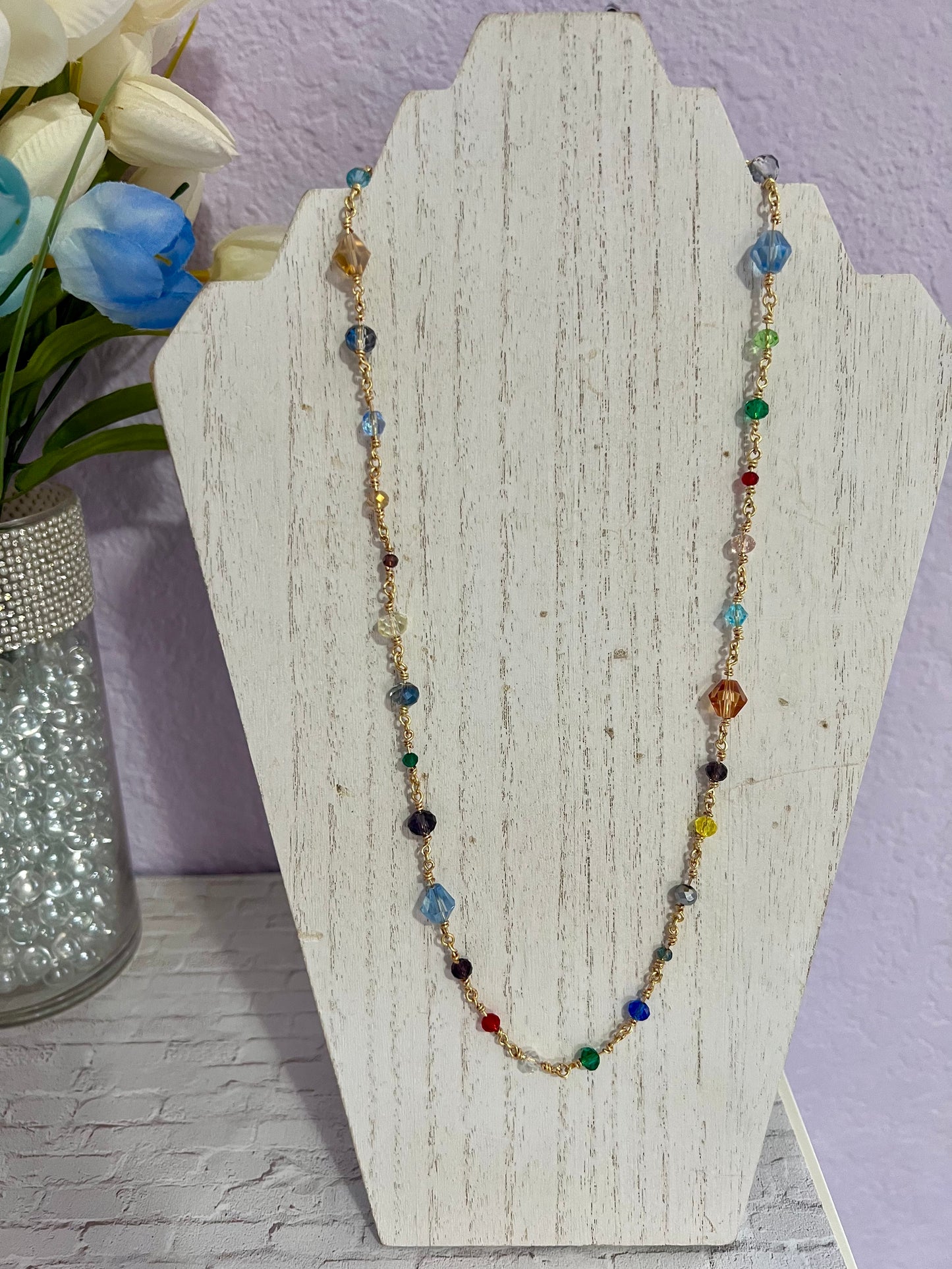 a necklace with multicolored beads on a stand