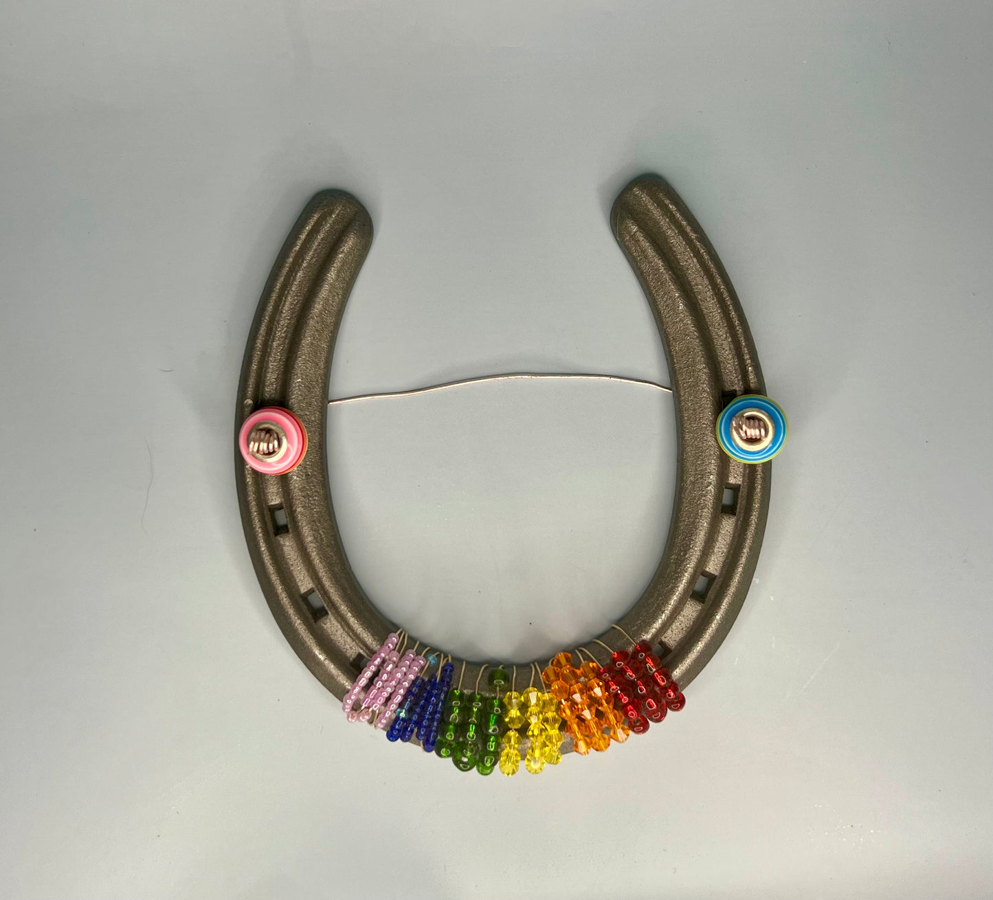 a metal horseshoe with a bunch of colorful beads on it