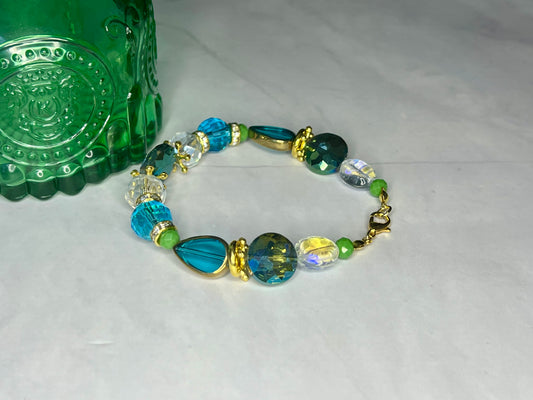 a green glass bottle sitting next to a bracelet