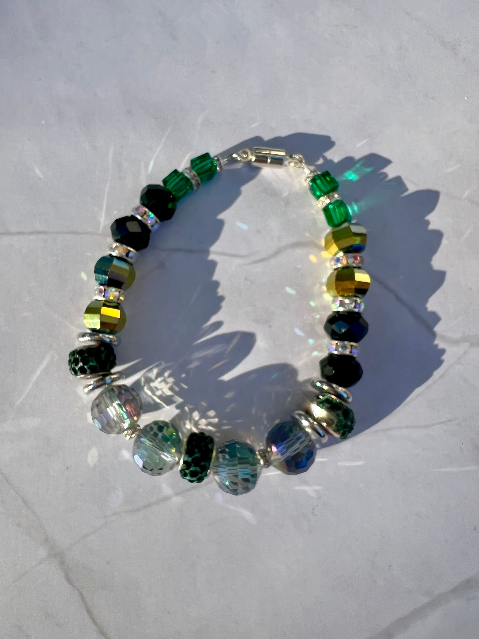 a green and yellow beaded bracelet on a white surface