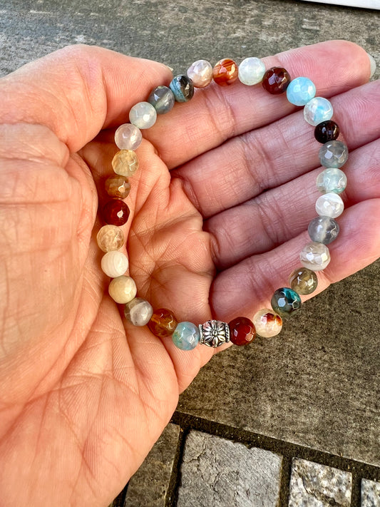 a person holding a beaded bracelet in their hand