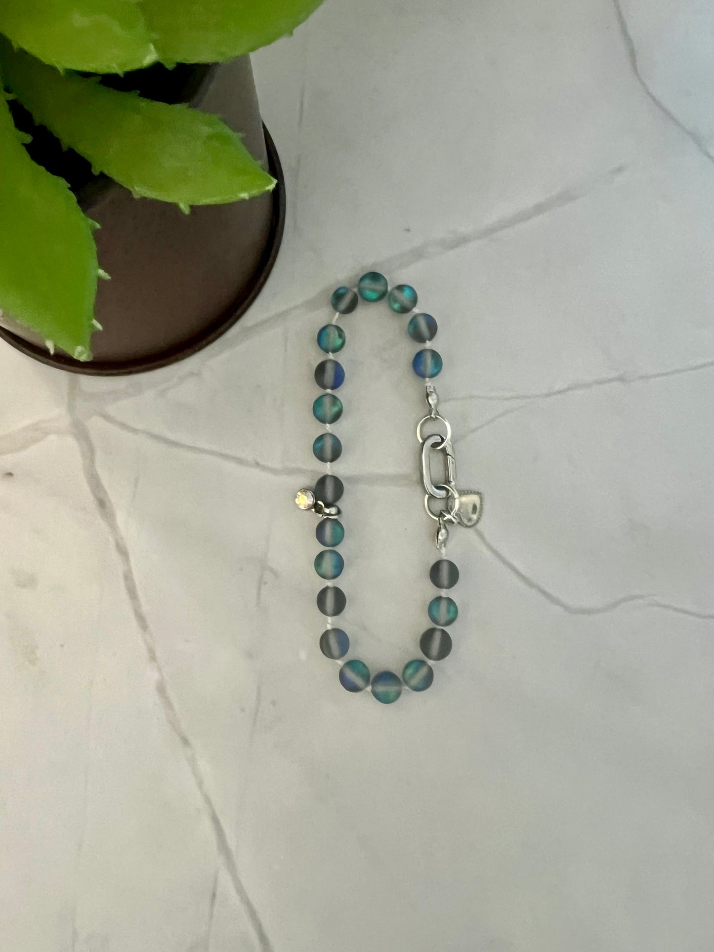 a blue beaded bracelet sitting next to a potted plant