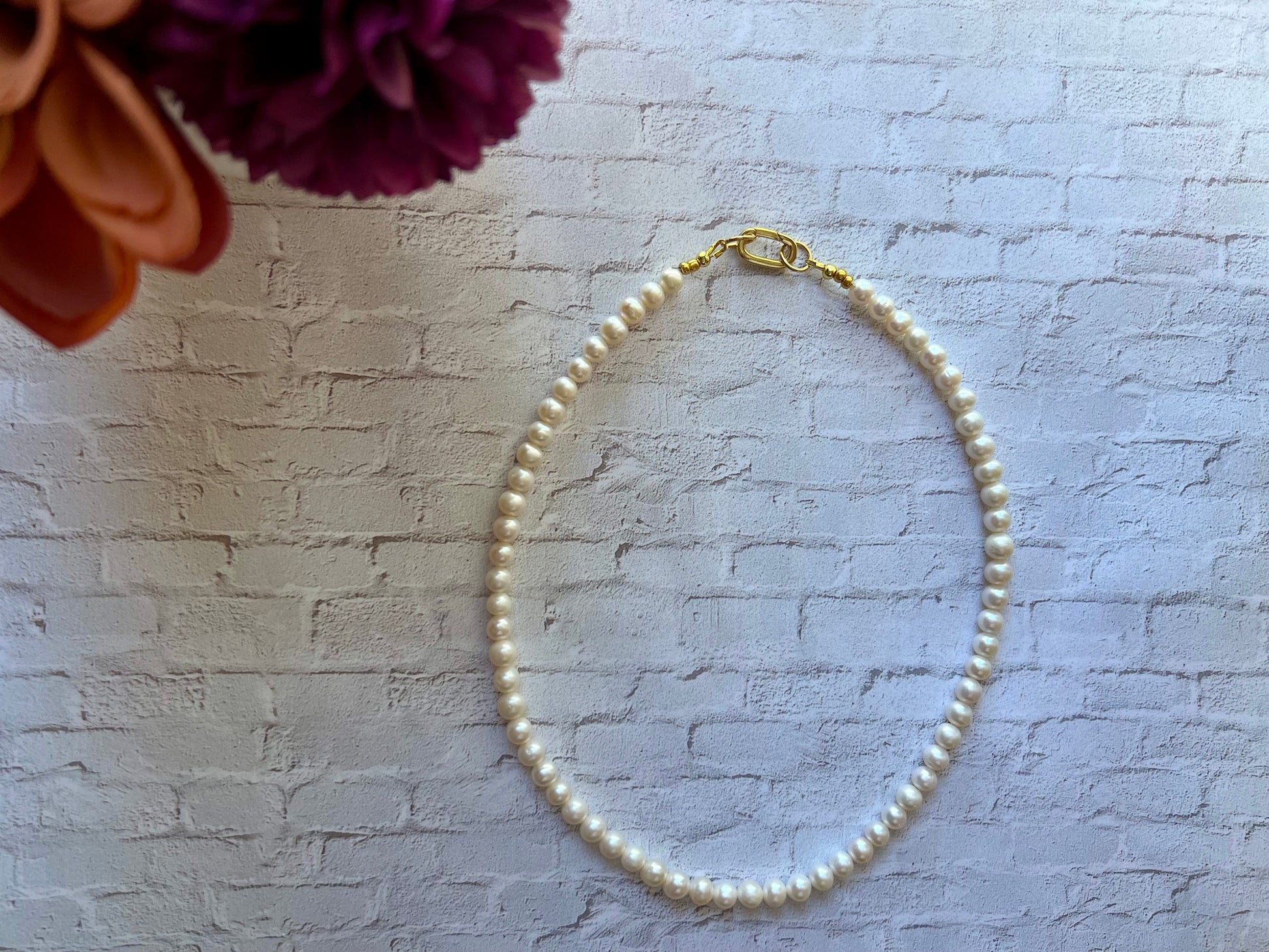 a white pearl bracelet on a gold plated chain