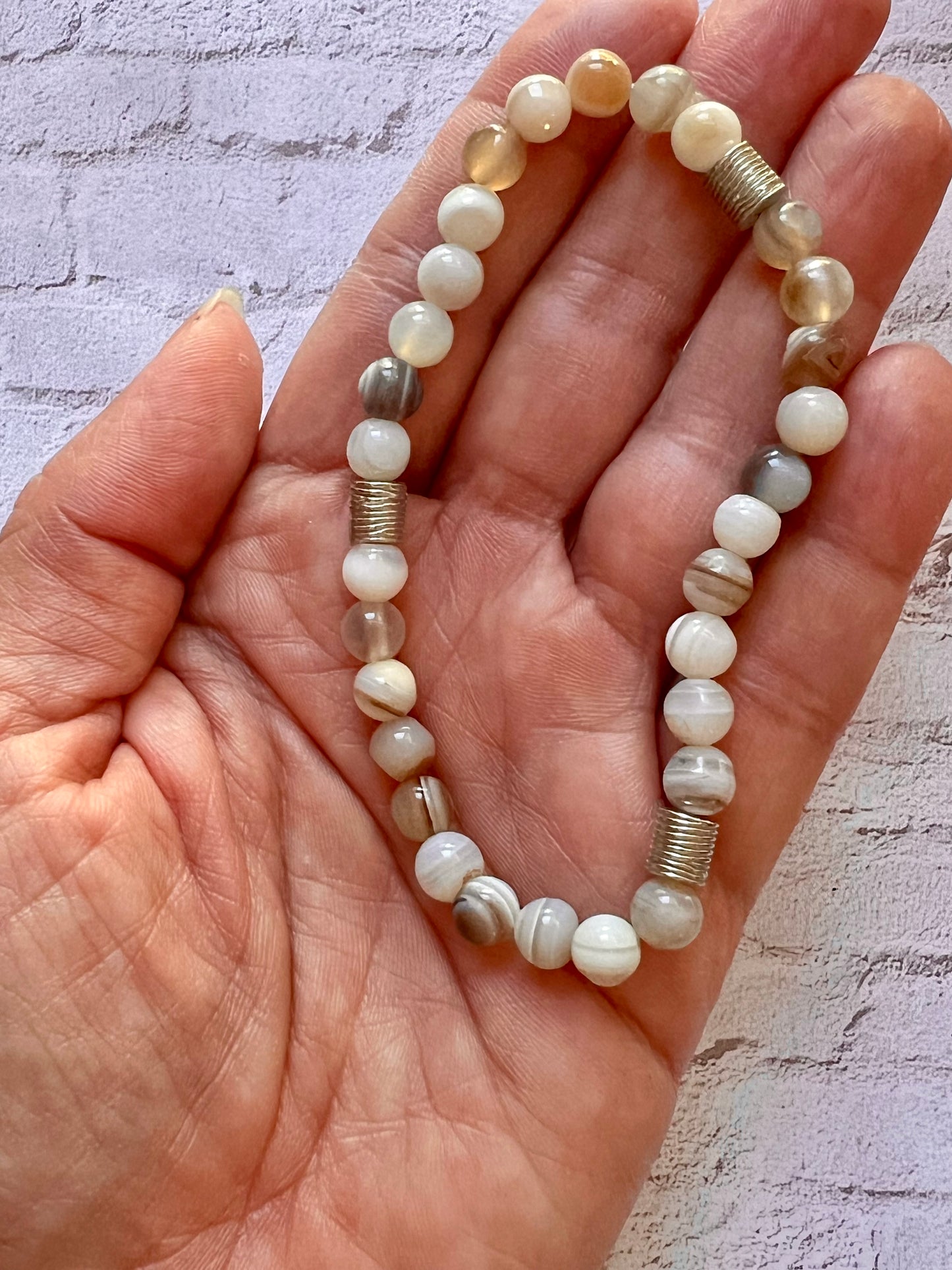 a woman's hand holding a beaded bracelet