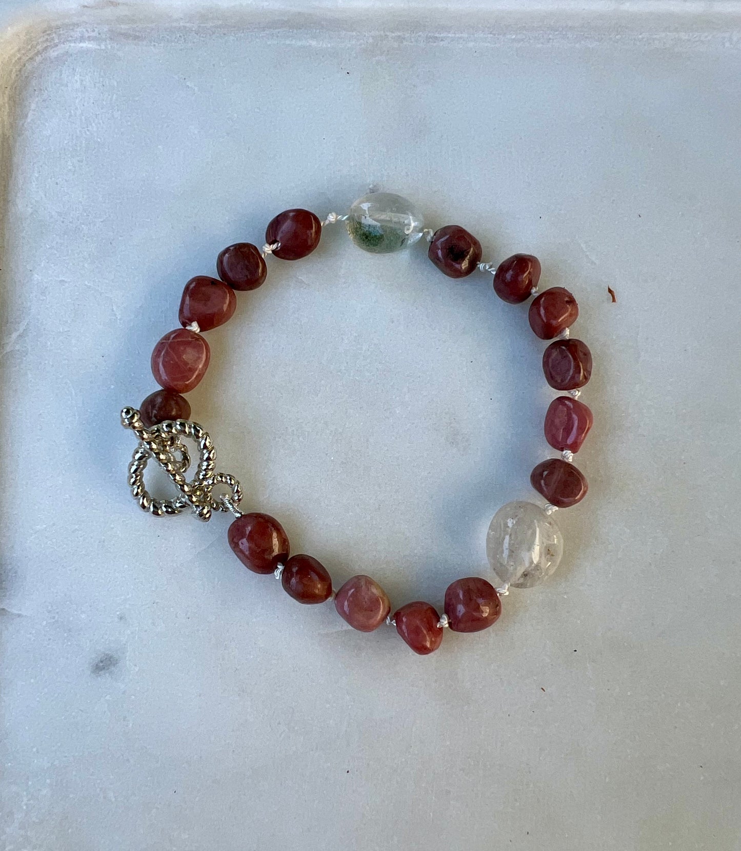 a red and white beaded bracelet with a heart charm