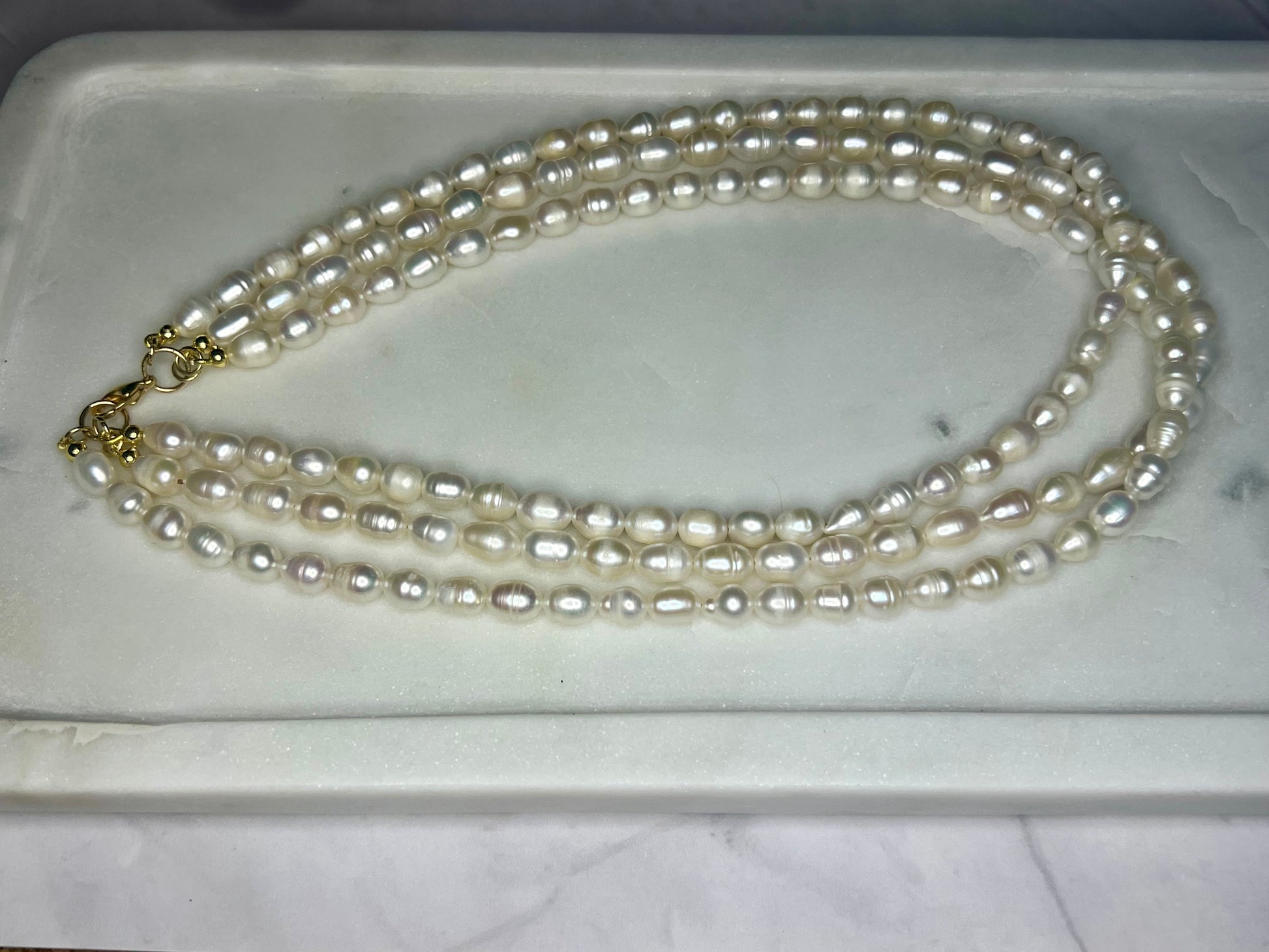 a three strand pearl necklace on a marble tray