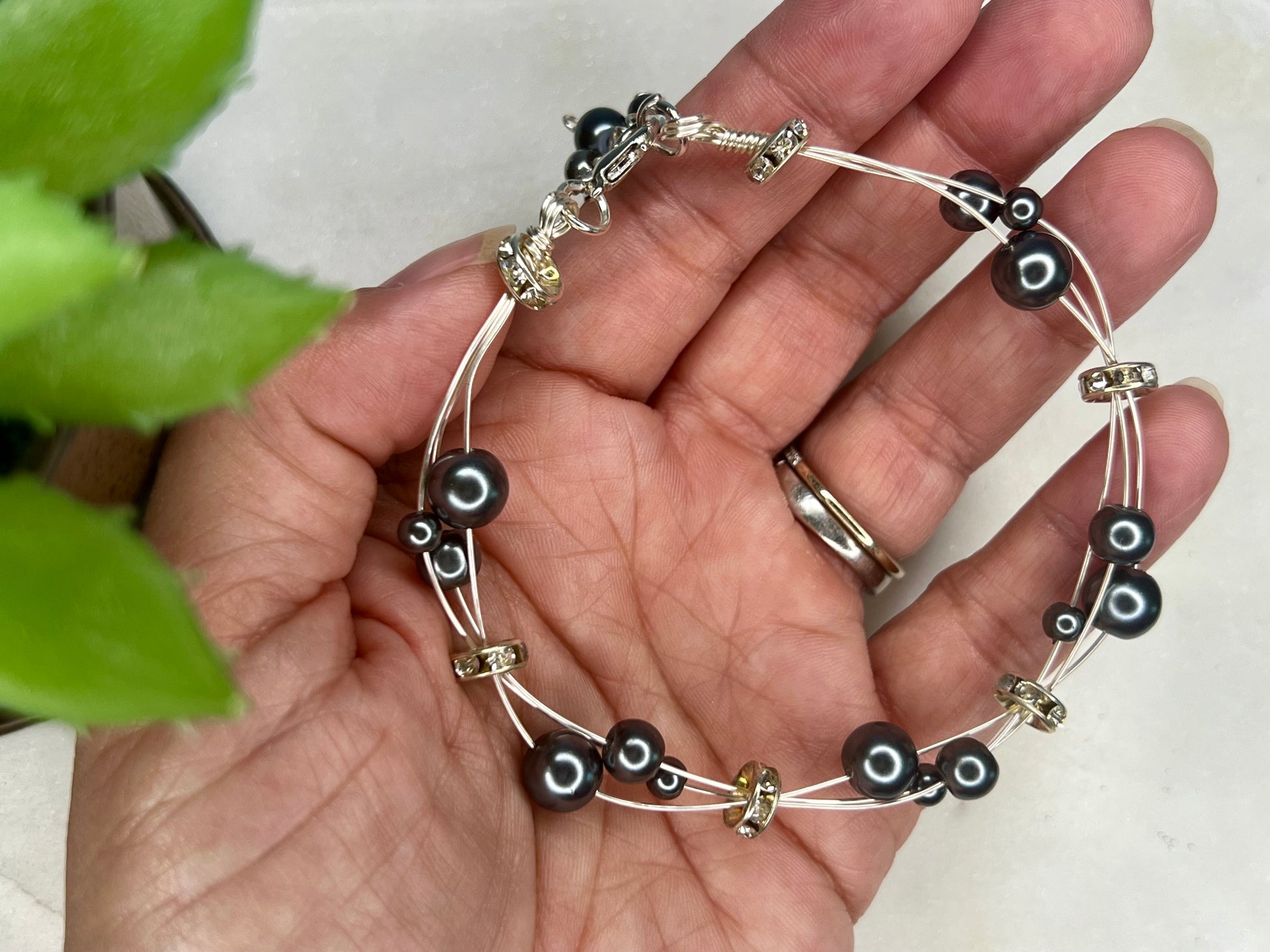 a hand holding a black and silver bracelet