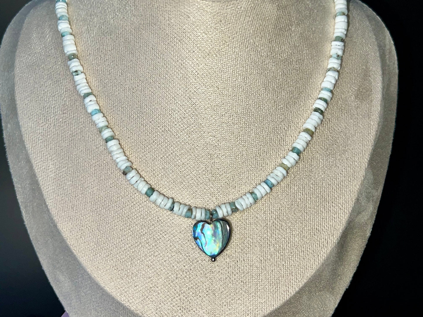 a necklace on a mannequin with a heart shaped pendant