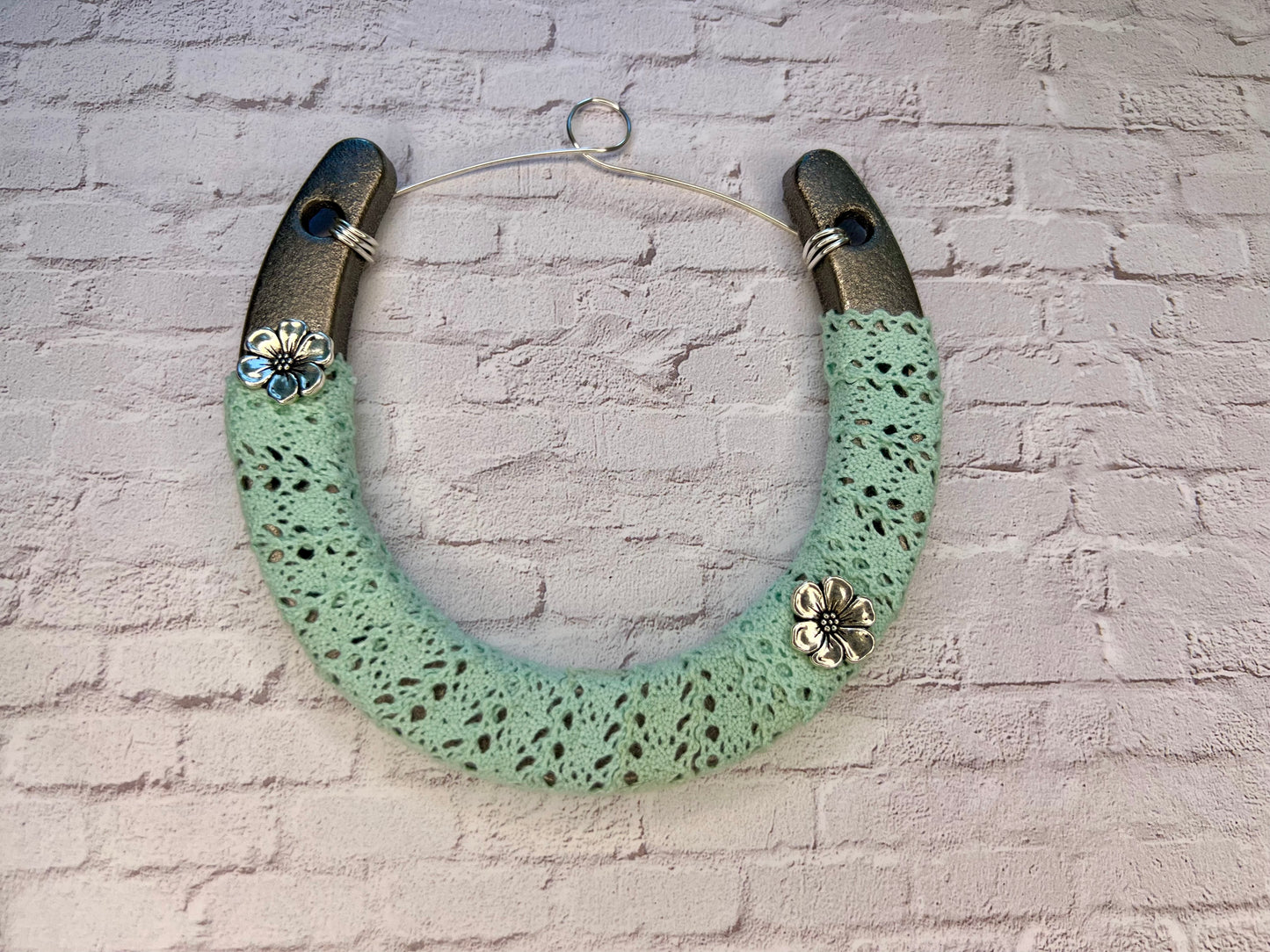 a green necklace hanging on a brick wall