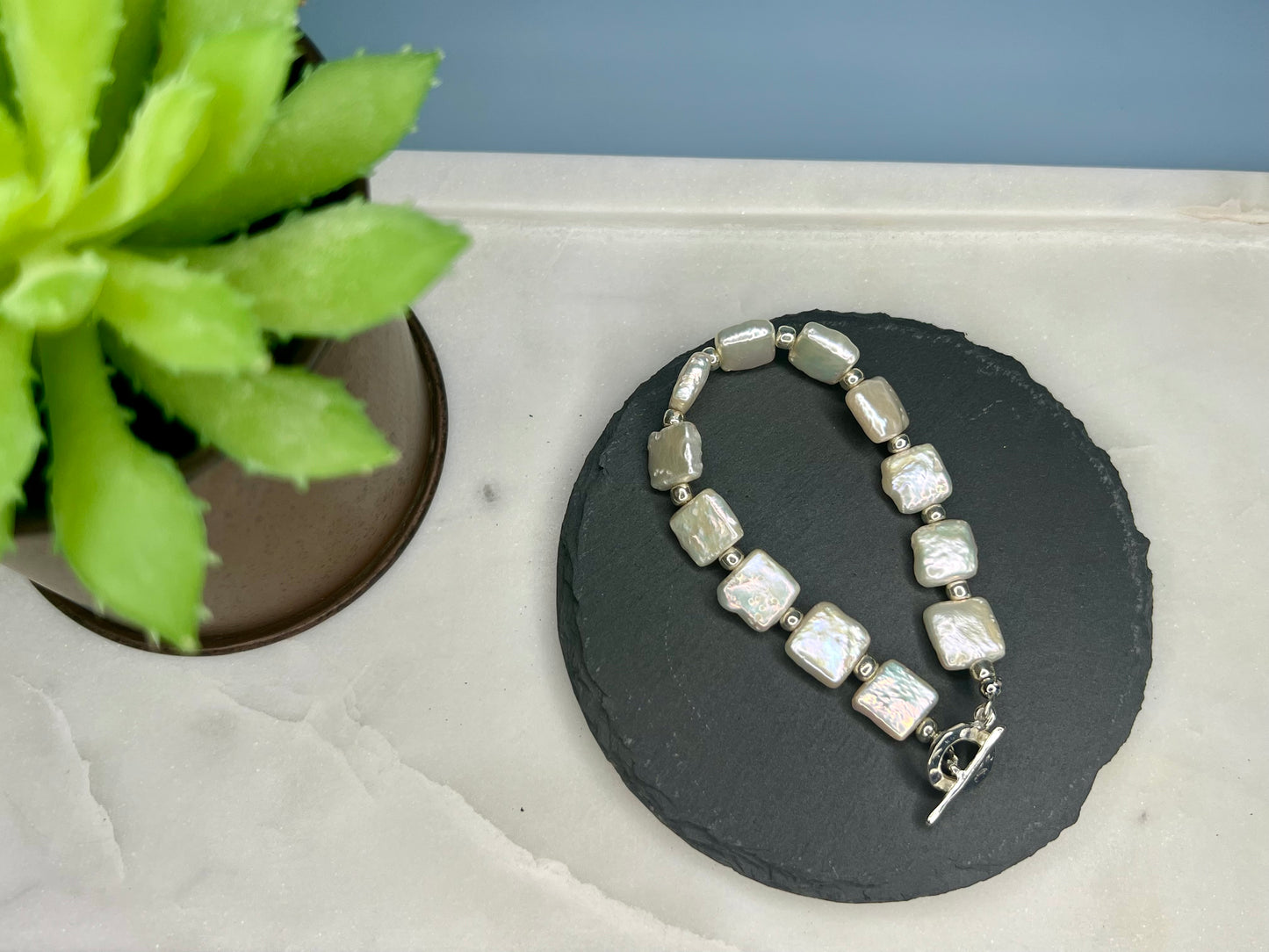 a necklace with pearls and a flower on a table