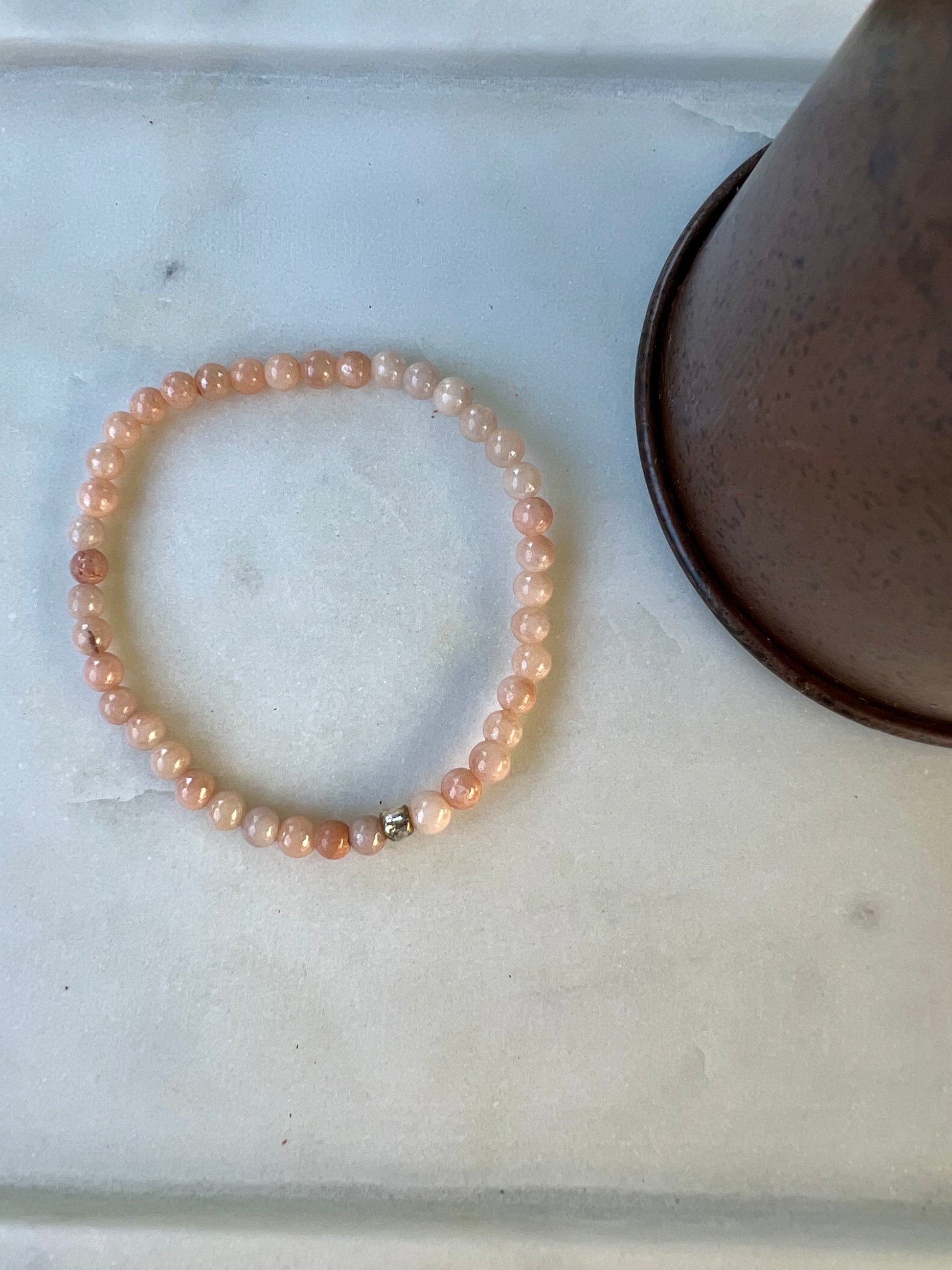 a pink beaded bracelet and a lamp on a table