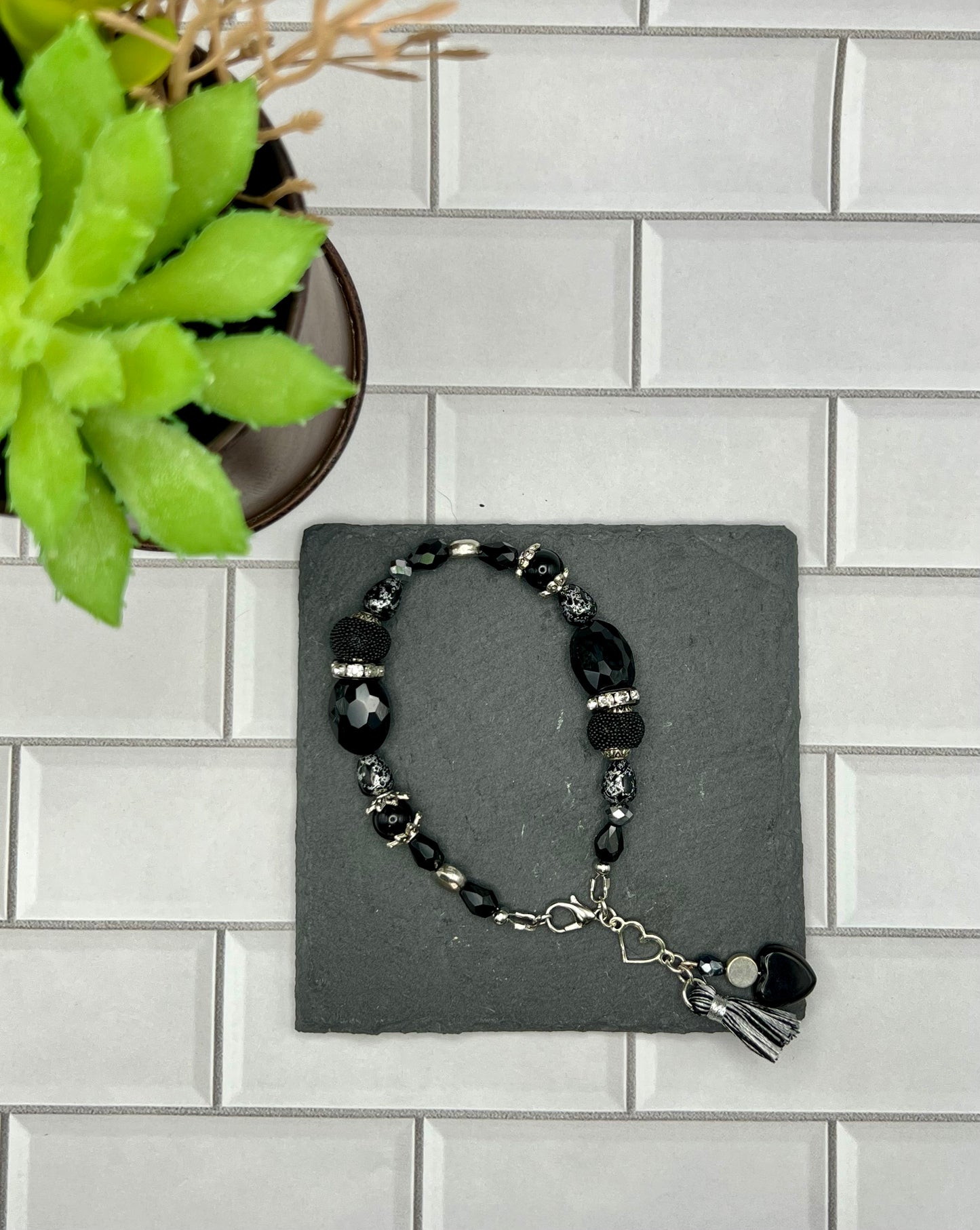 a black beaded bracelet with a cross on it