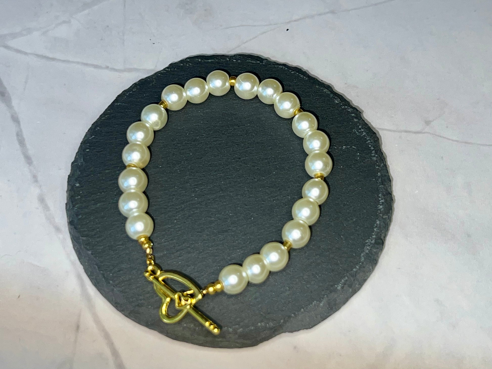 a pearl bracelet with a gold cross charm