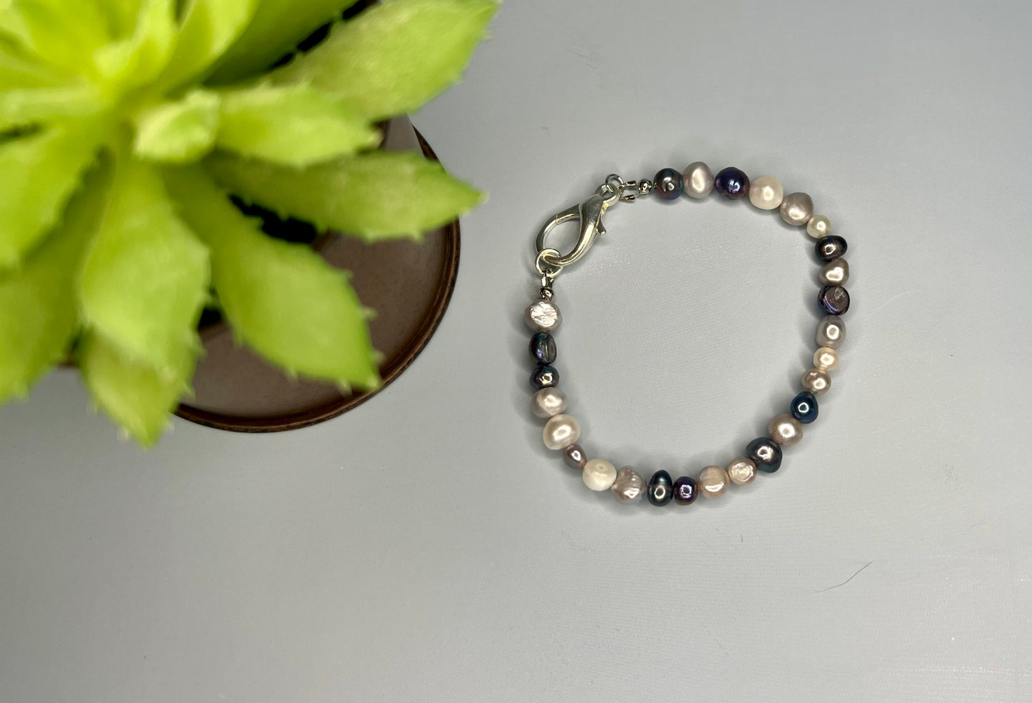 a bracelet with pearls and a flower on a table