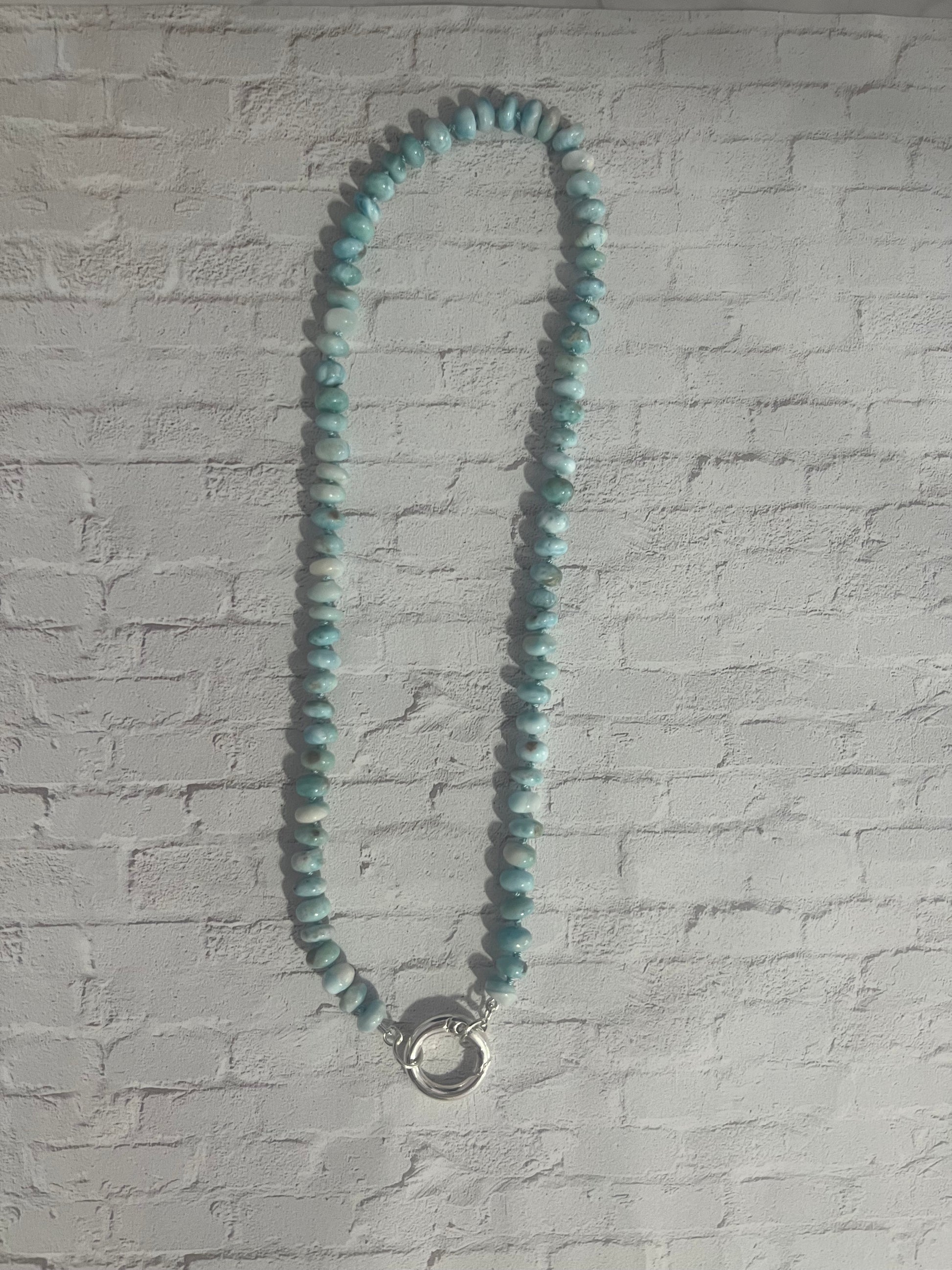 a blue beaded necklace is hanging on a wall