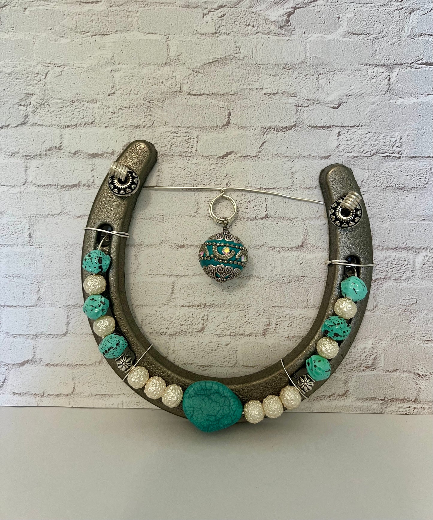 a horseshoe shaped necklace with turquoise and white beads