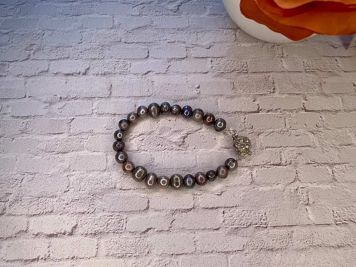 a beaded bracelet with a flower on a brick wall