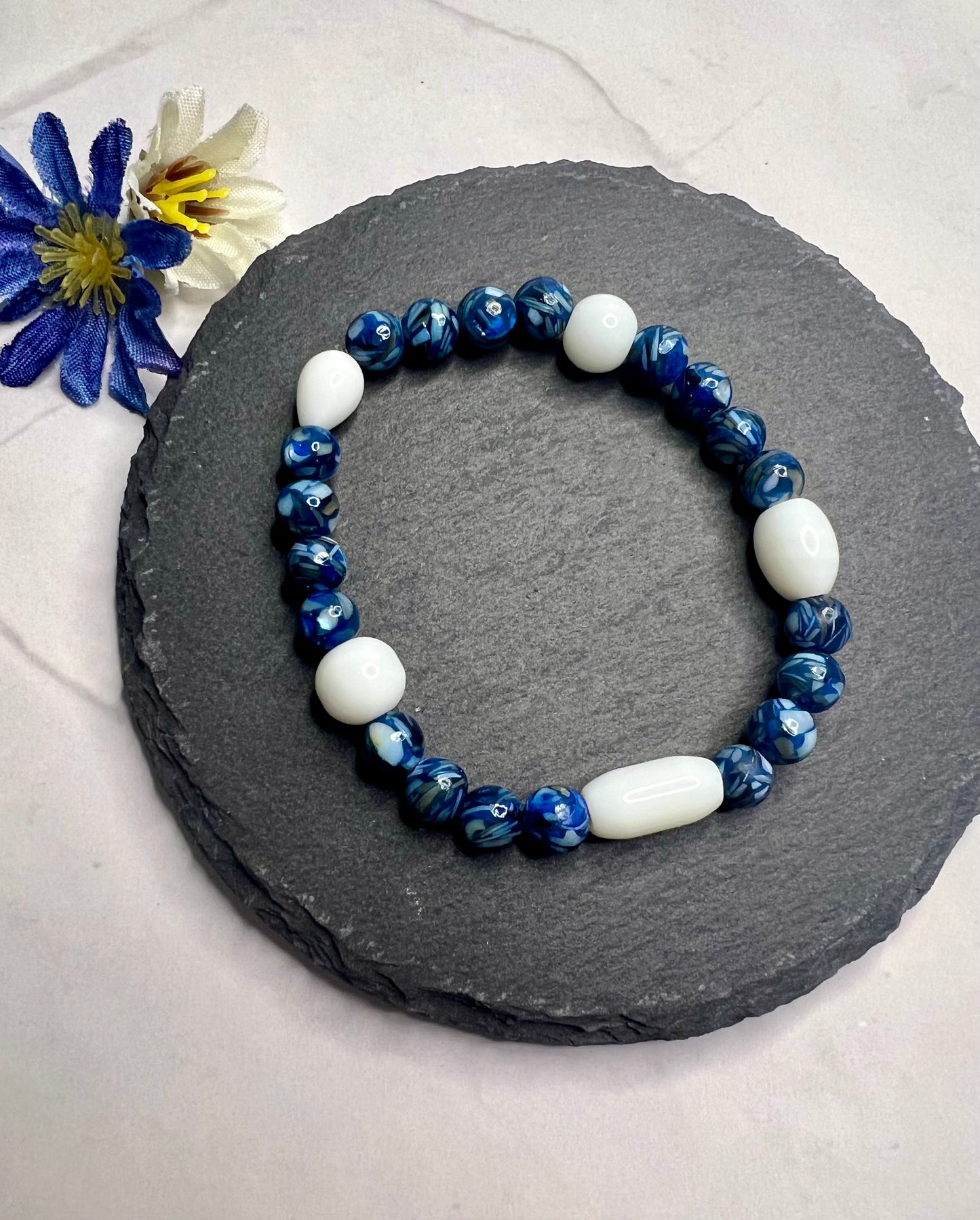 a blue and white beaded bracelet on a rock