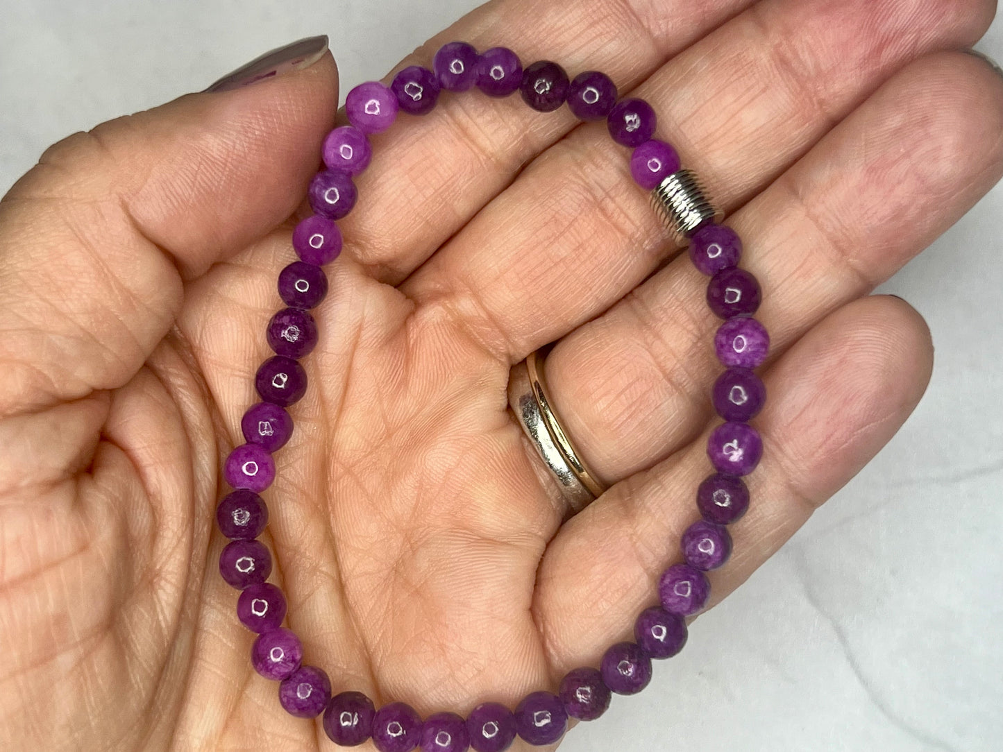 a person holding a purple beaded bracelet