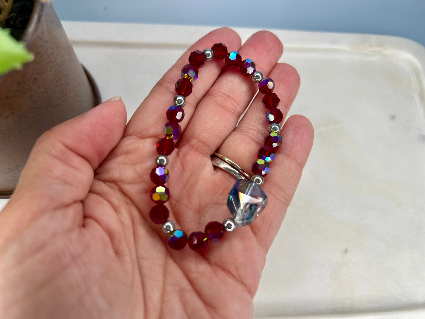 a person holding a beaded bracelet in their hand