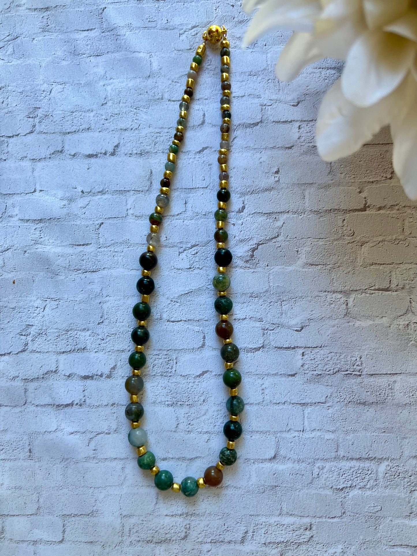 a long beaded necklace with green and brown beads