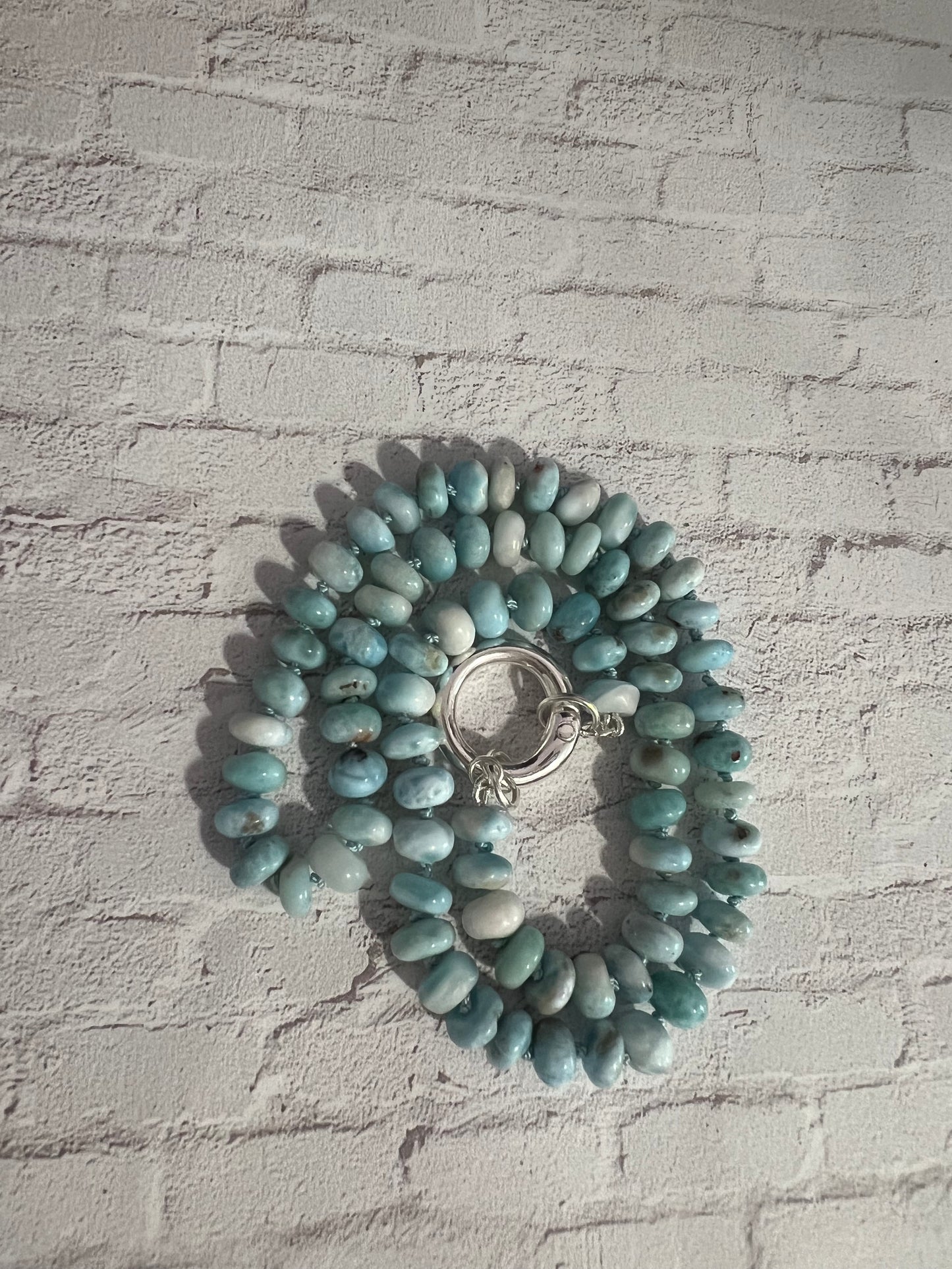 a bracelet with a ring on a white brick wall