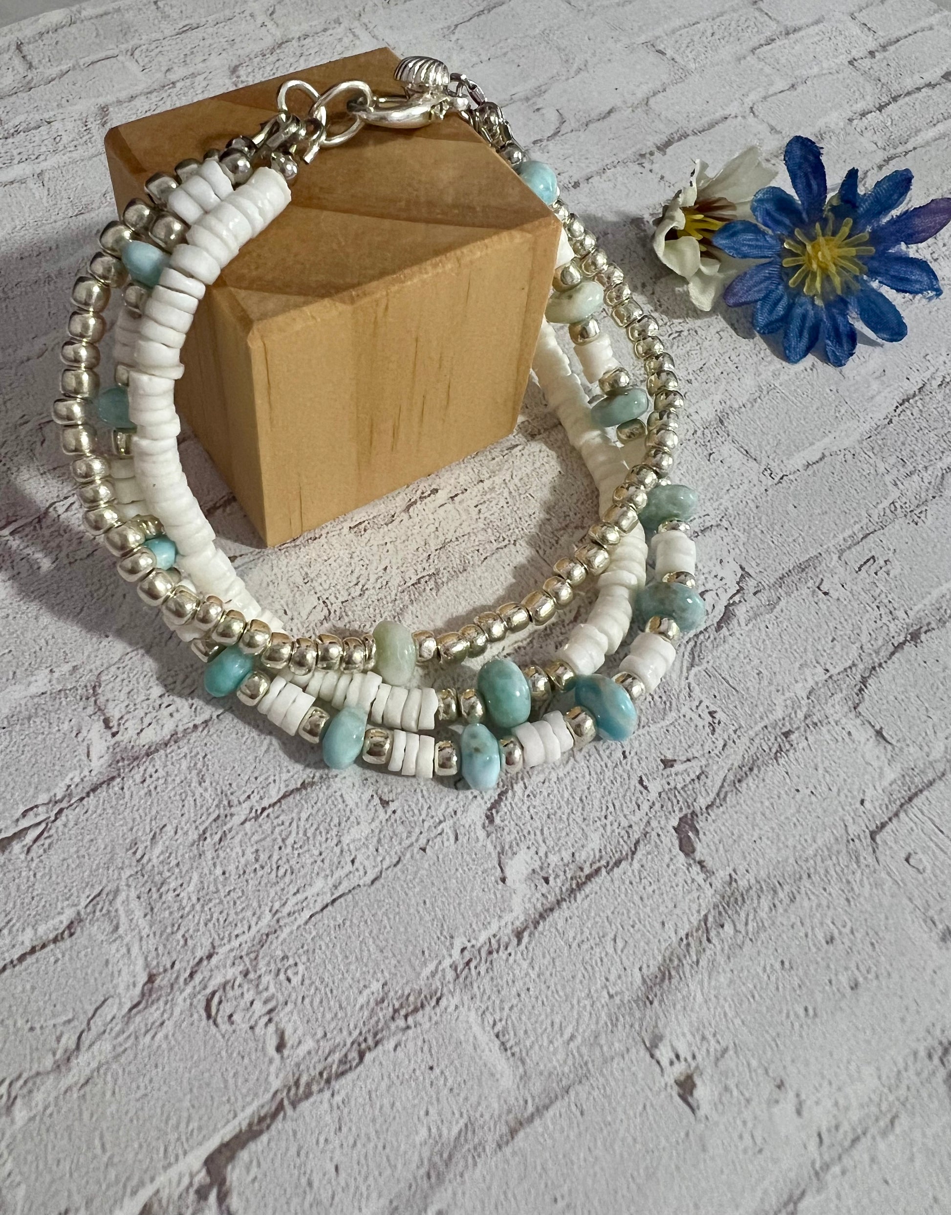 a bracelet with beads and a flower on a table