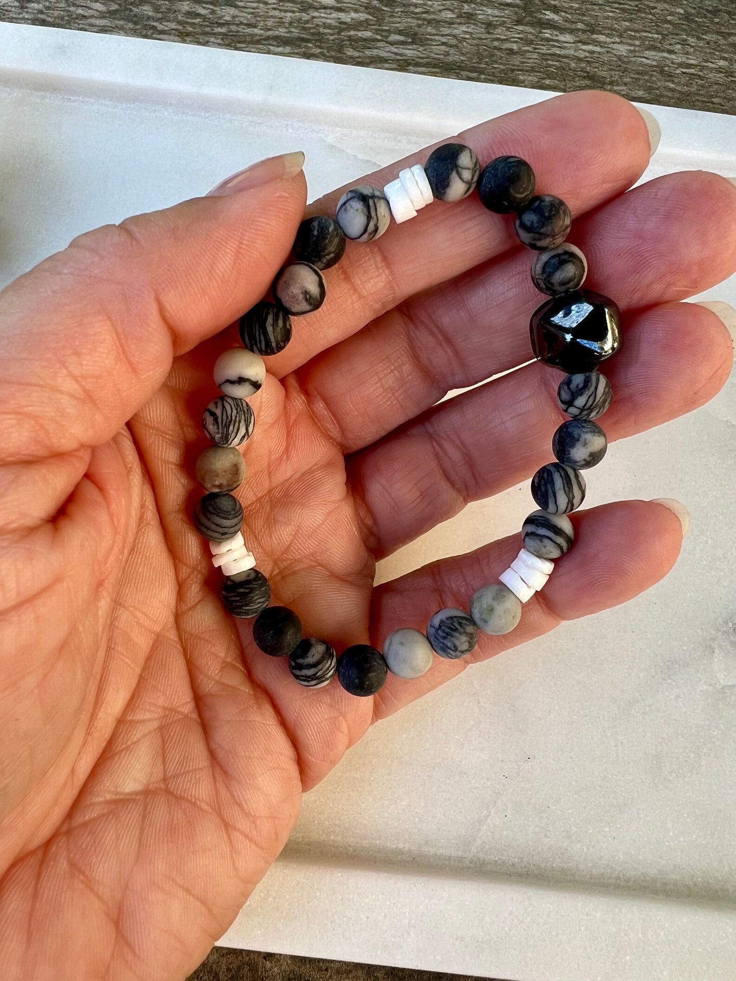 a person holding a beaded bracelet in their hand