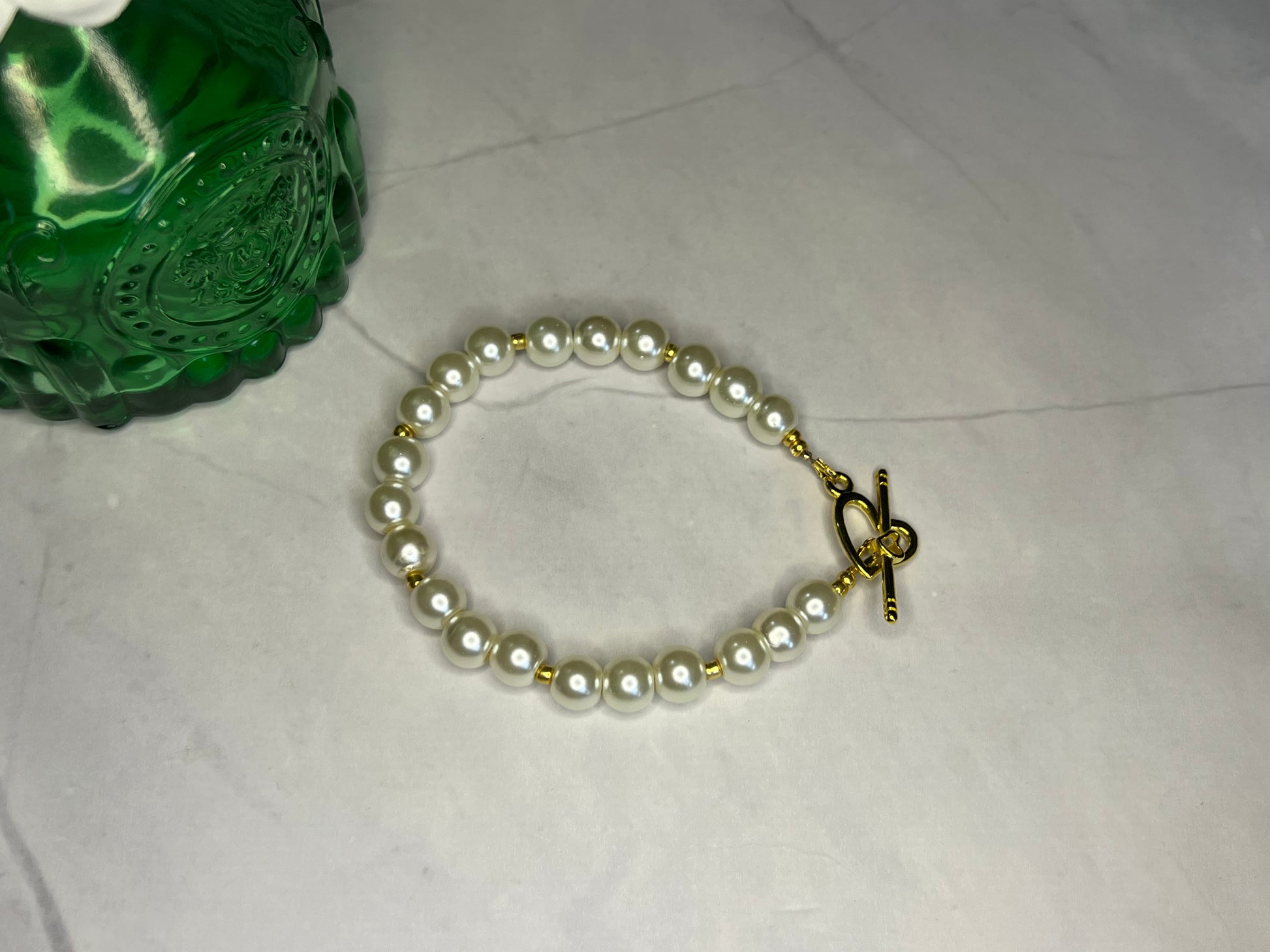 a white bracelet with a gold clasp and pearls