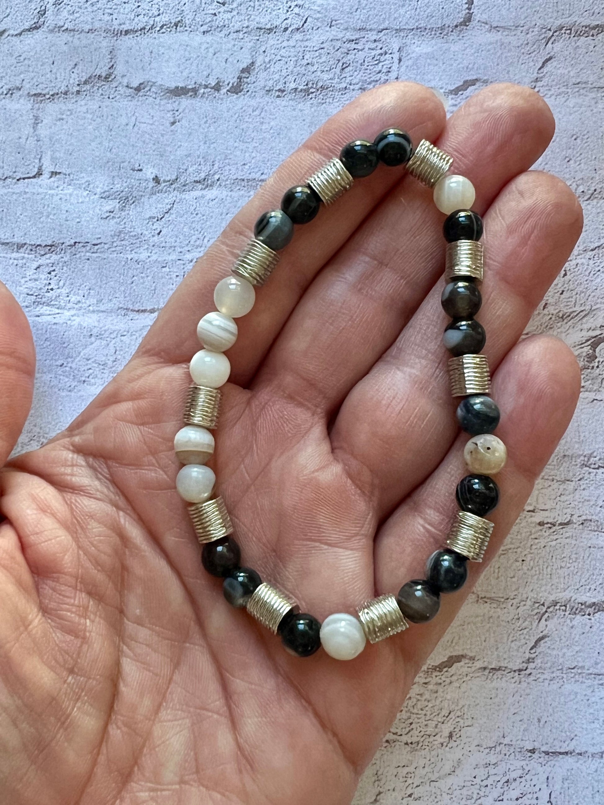 a hand holding a bracelet with black and white beads